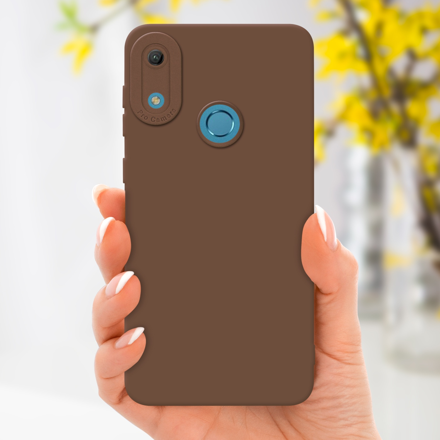 Main tenant une coque marron avec une seule caméra, fleurs jaunes en arrière-plan.
