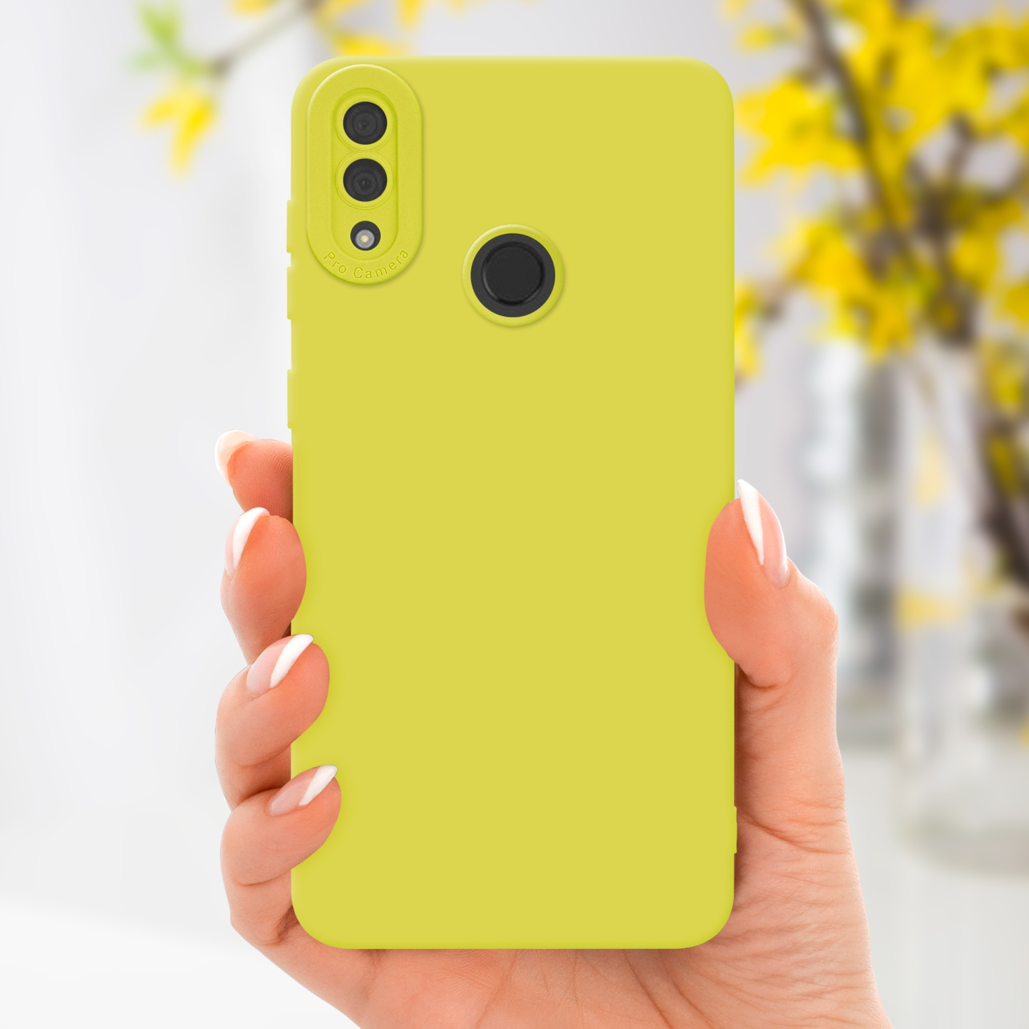 Main tenant une coque de téléphone jaune avec caméra pro. Fleurs jaunes en arrière-plan.