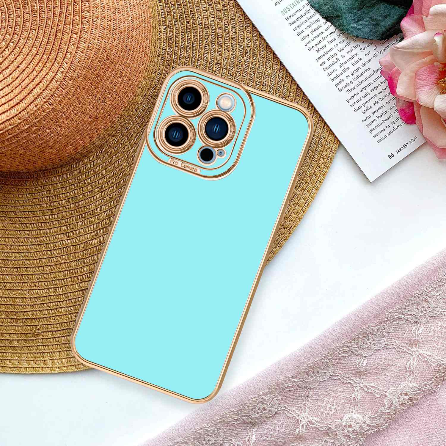Ein Telefon in einer blauen Hülle, das auf einem Strohhut und einem rosa Tuch liegt.
