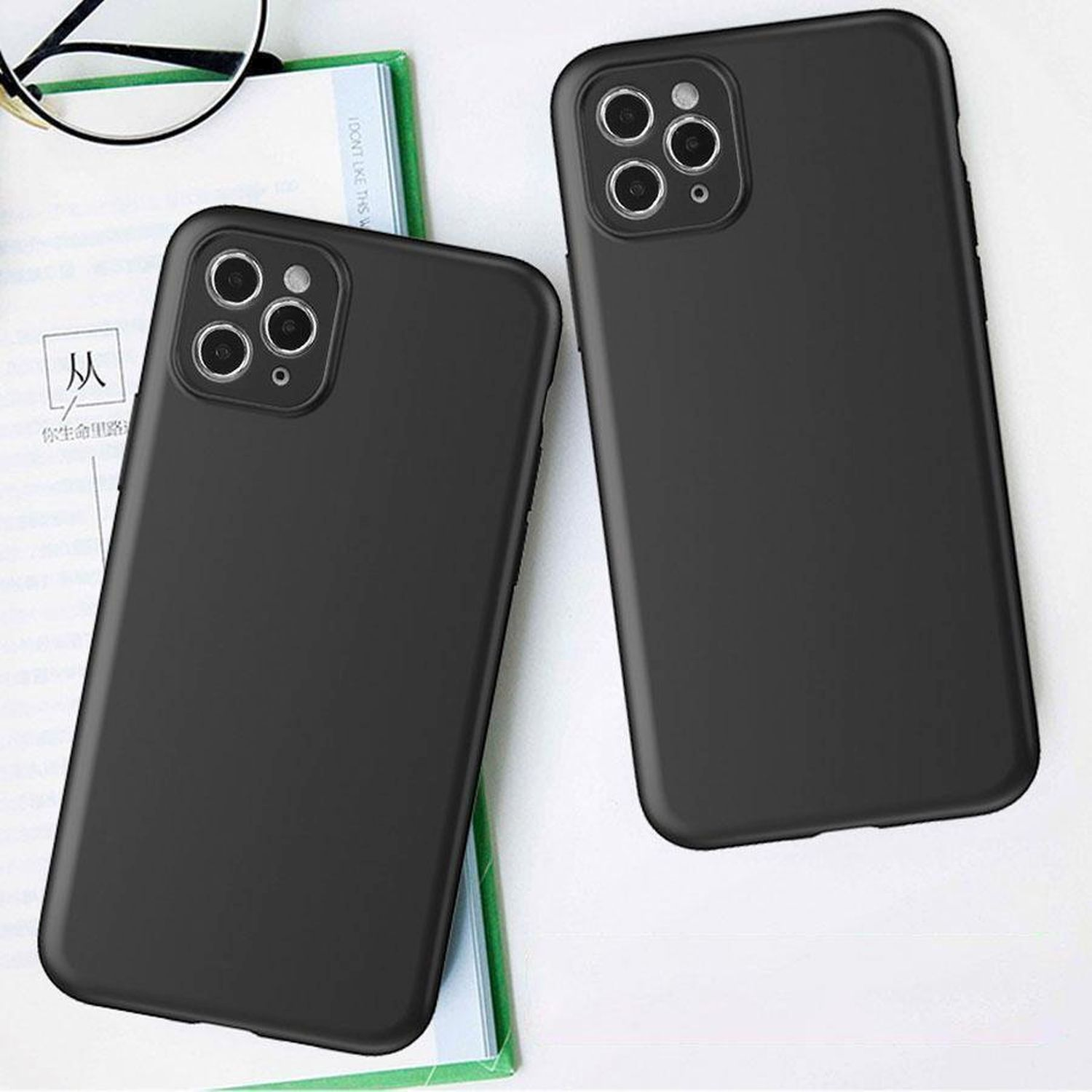 Zwei schwarze Handyhüllen mit Telefonen auf einem Tisch, Gläser daneben.