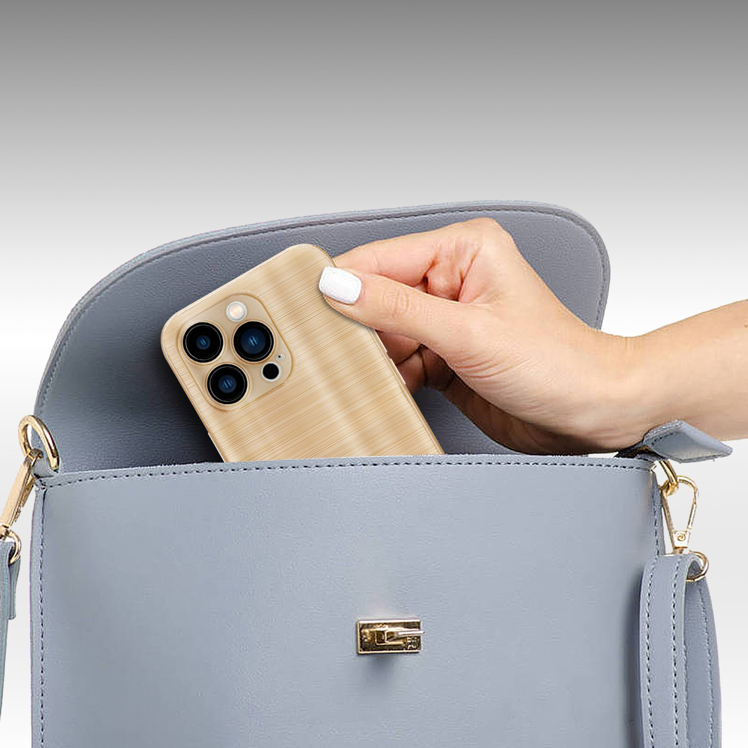 Eine Hand, die ein Telefon in eine hellblaue Handtasche legt. Das Telefon hat eine goldene Hülle.