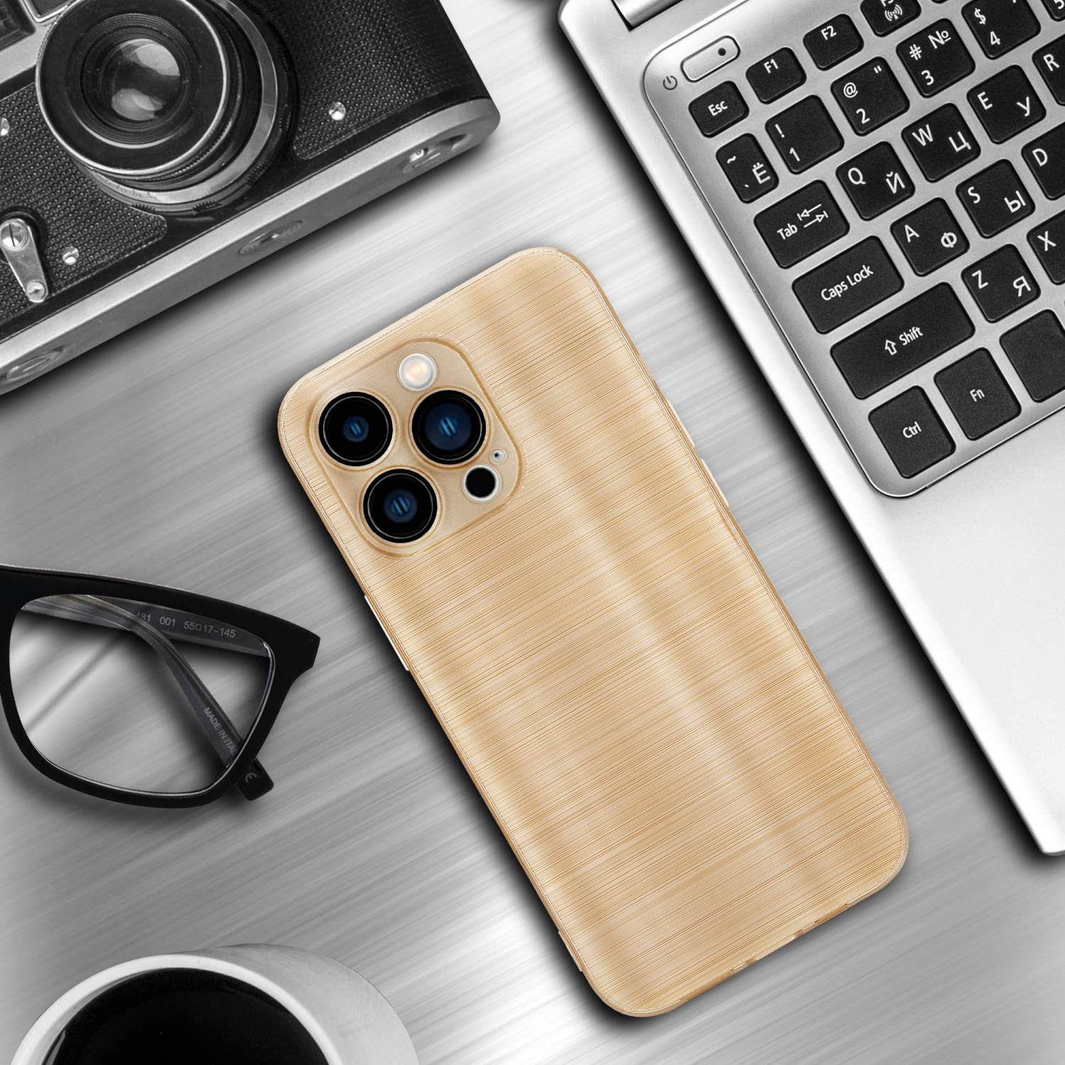 Goldene Handyhülle und ein Laptop mit Kamera, Brille und einer Tasse auf dem Tisch.