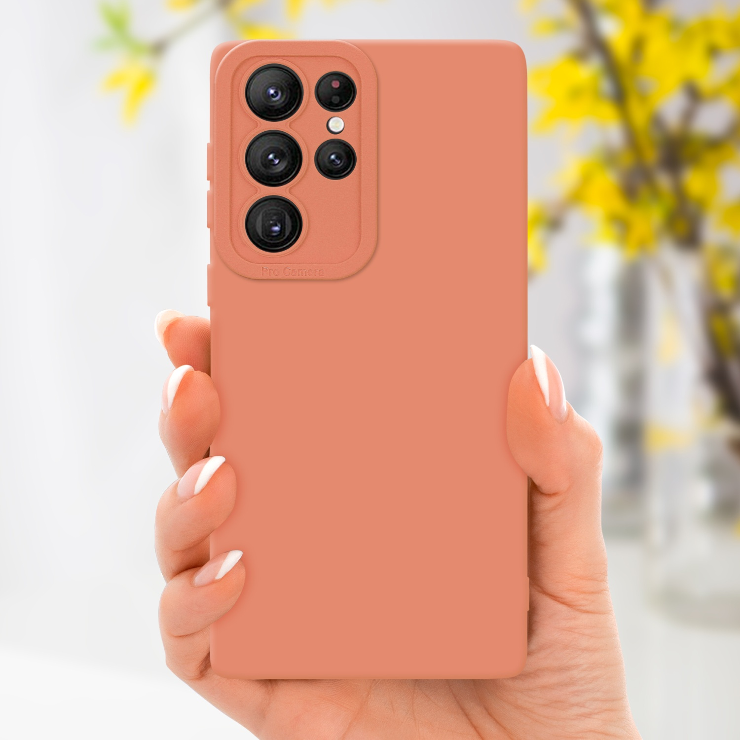 Una mano che tiene una custodia per telefono color pesca con più obiettivi della fotocamera.