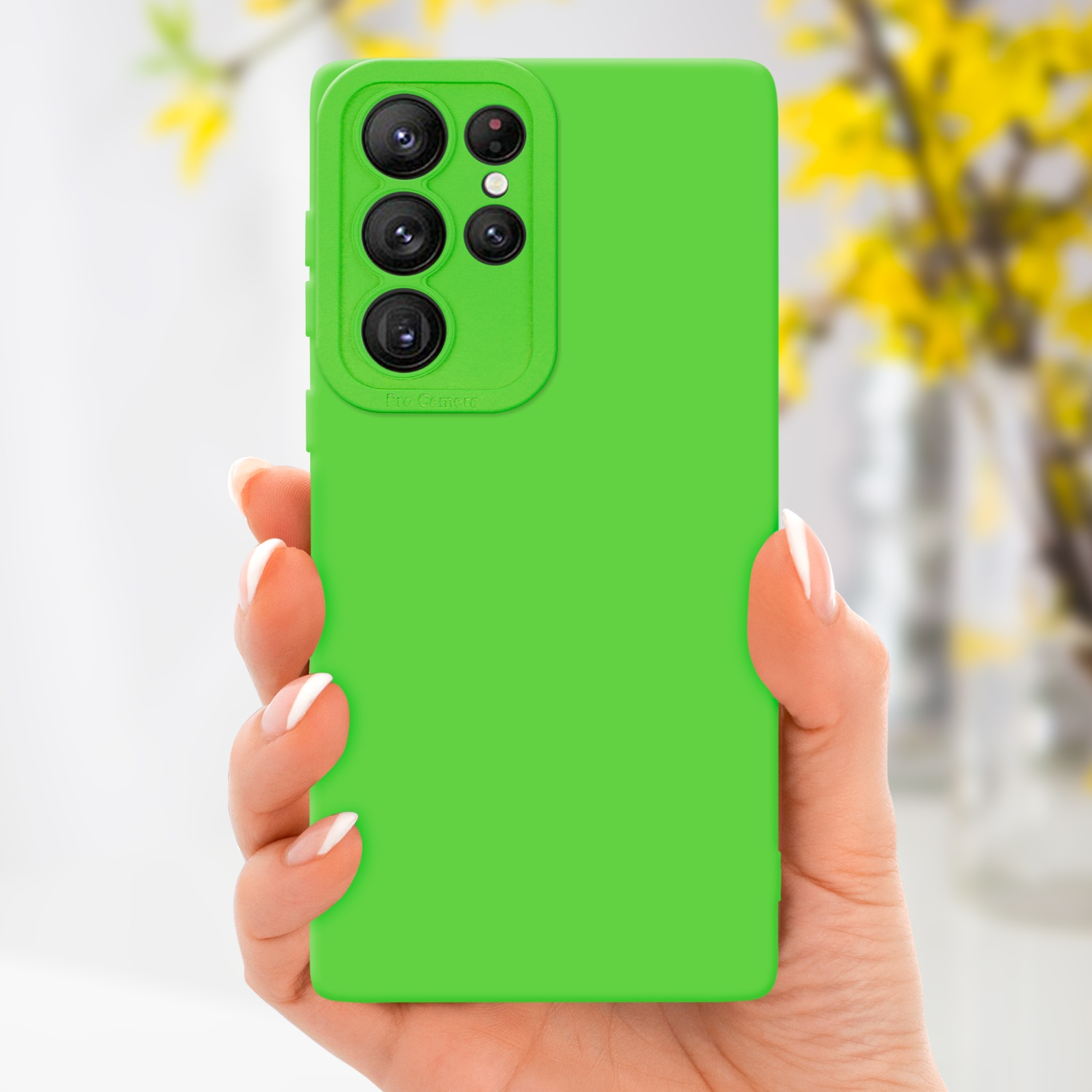 Mano che tiene un telefono verde con custodia verde. Fiori gialli sullo sfondo.