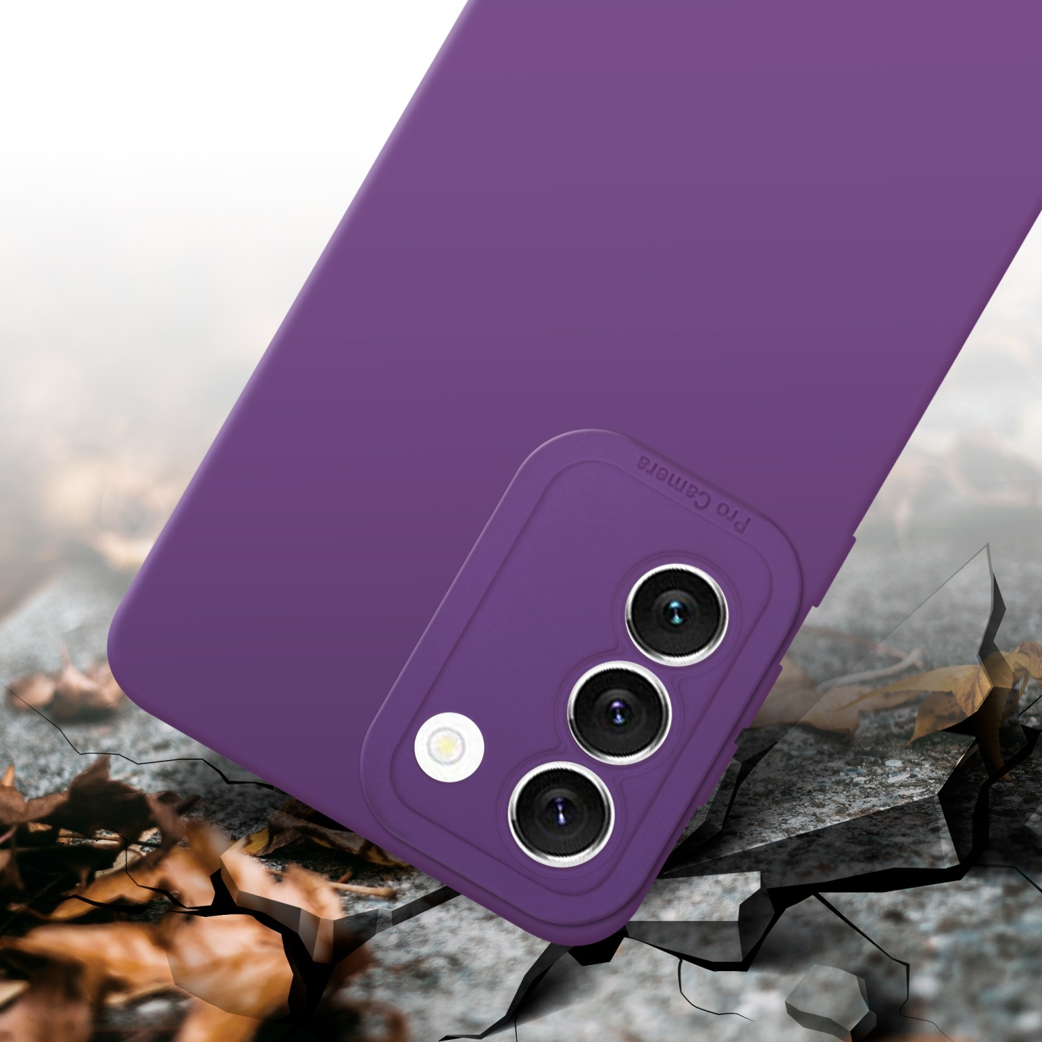 Une coque de téléphone violette avec une découpe pour l'appareil photo tombe, avec des feuilles au sol. L'arrière-plan est flou.
