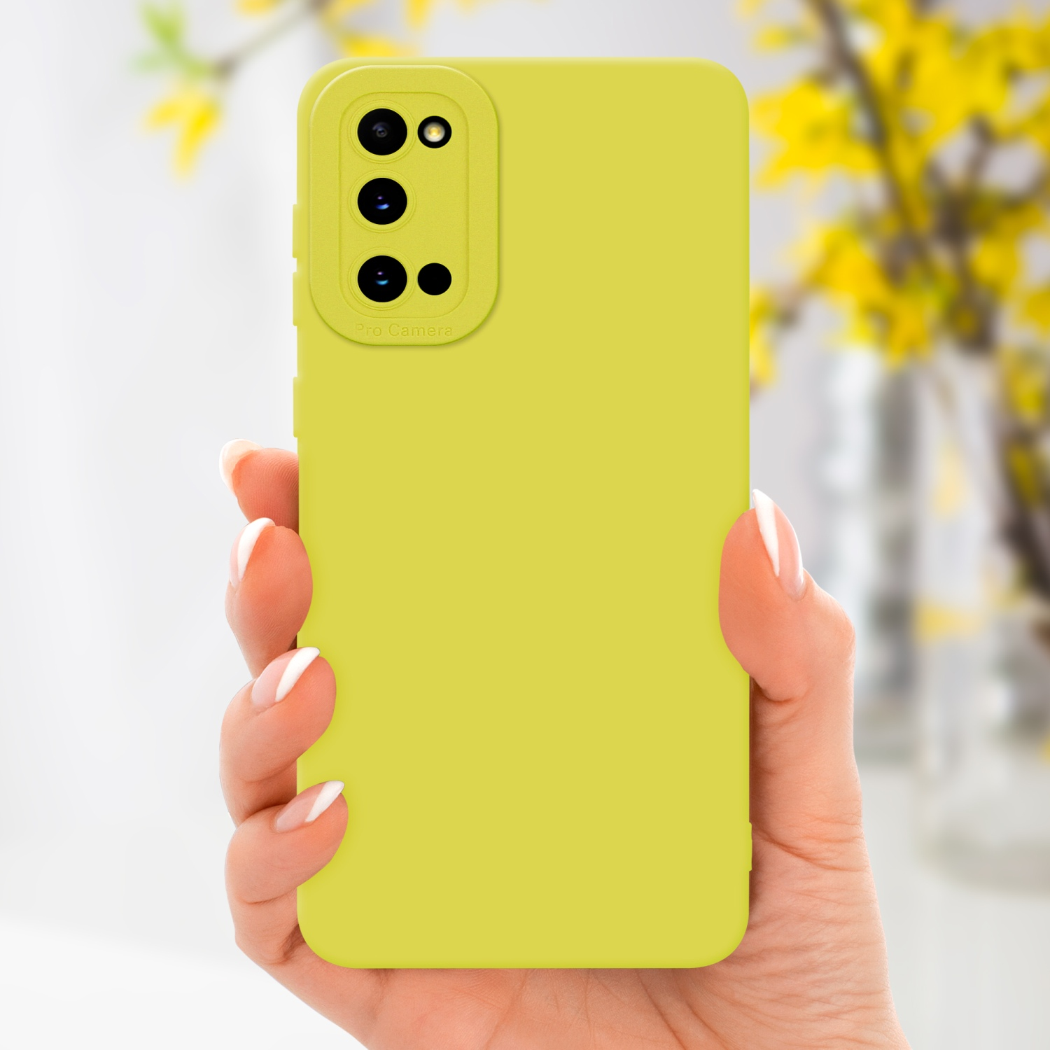 Una mano che tiene una custodia per telefono verde chiaro con un ritaglio per la fotocamera. Fiori gialli sfocati sullo sfondo.