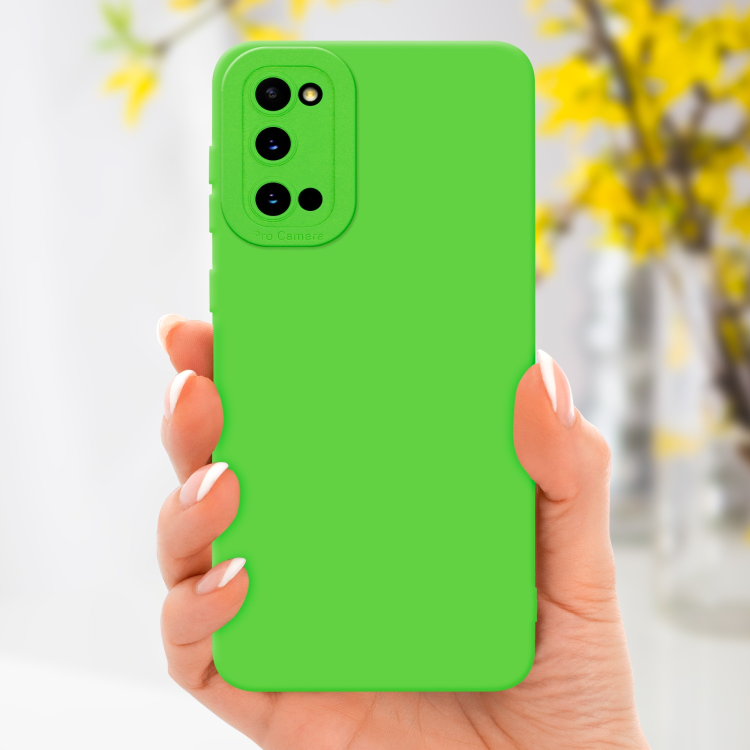 Coque de téléphone verte dans une main, avec un arrière-plan flou. Fleurs jaunes visibles en arrière-plan.