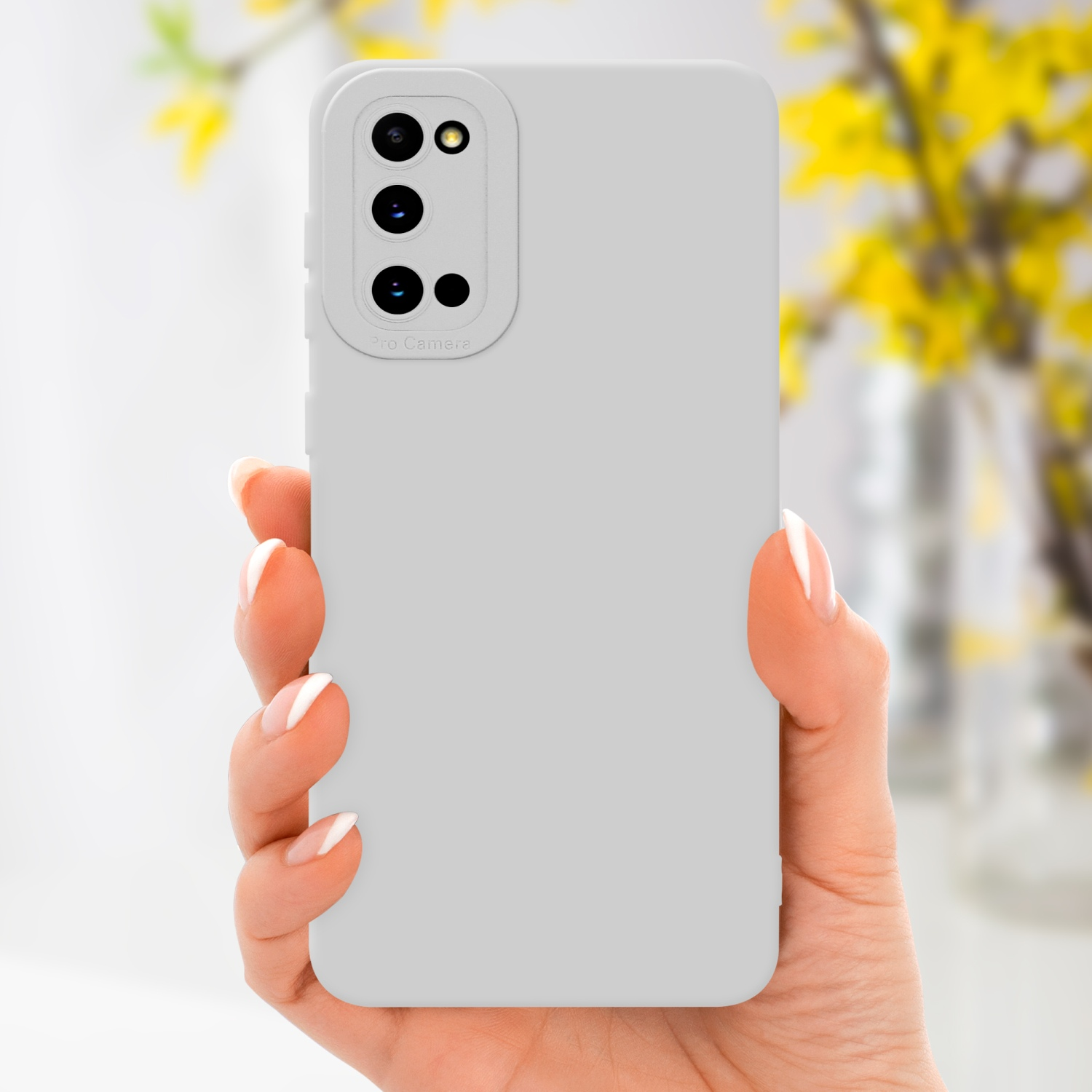 Mano che tiene una custodia per telefono grigia con un ritaglio per la fotocamera. Fiori gialli sullo sfondo.