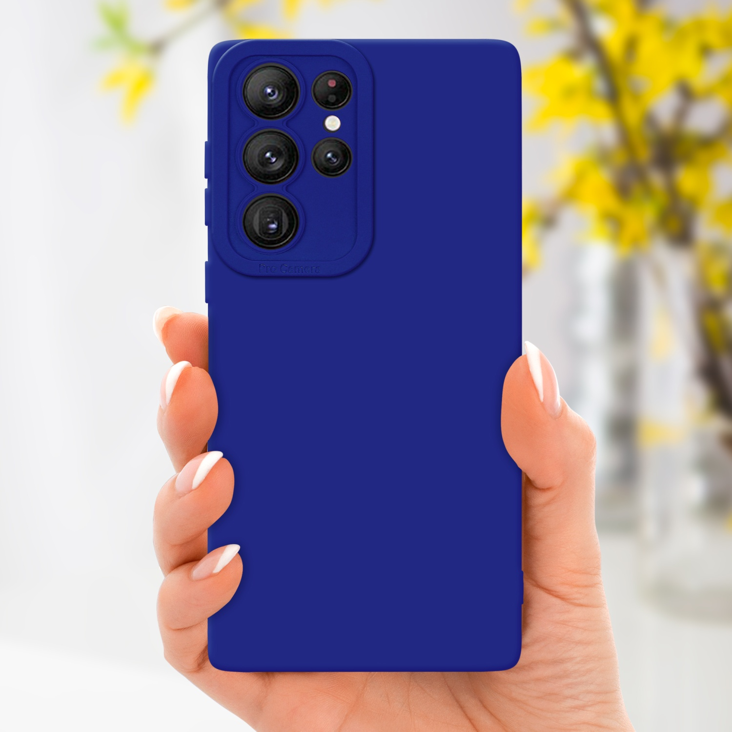 Main tenant un étui de téléphone bleu avec des objectifs de caméra. Fleurs jaunes en arrière-plan.