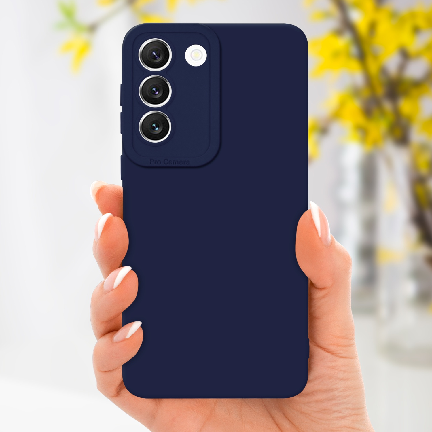 Une main tenant une coque de téléphone bleu foncé avec l'appareil photo. Fleurs jaunes en fond.