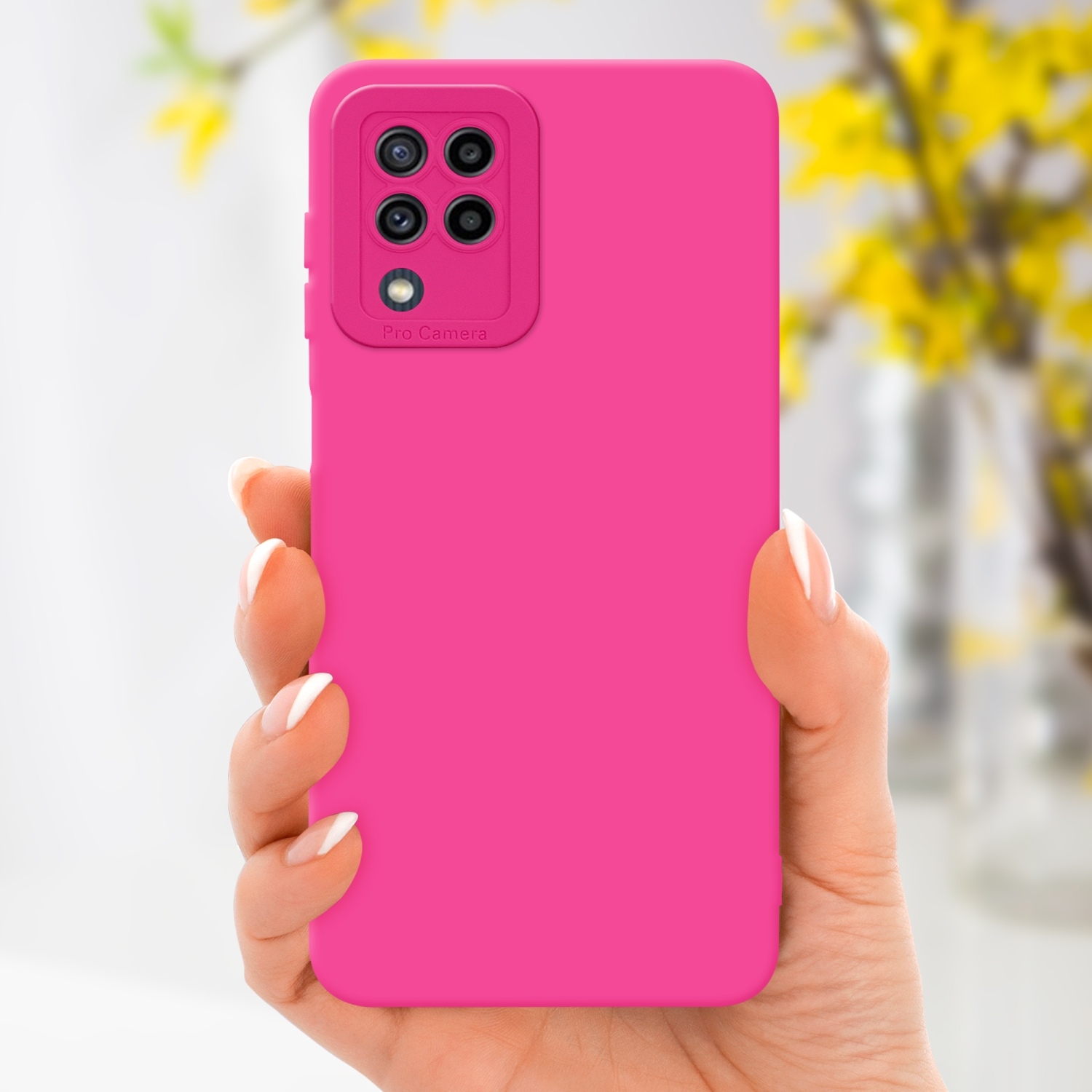 Mano che tiene un telefono rosa con sporgenza della fotocamera. Fiori gialli sfocati sullo sfondo.