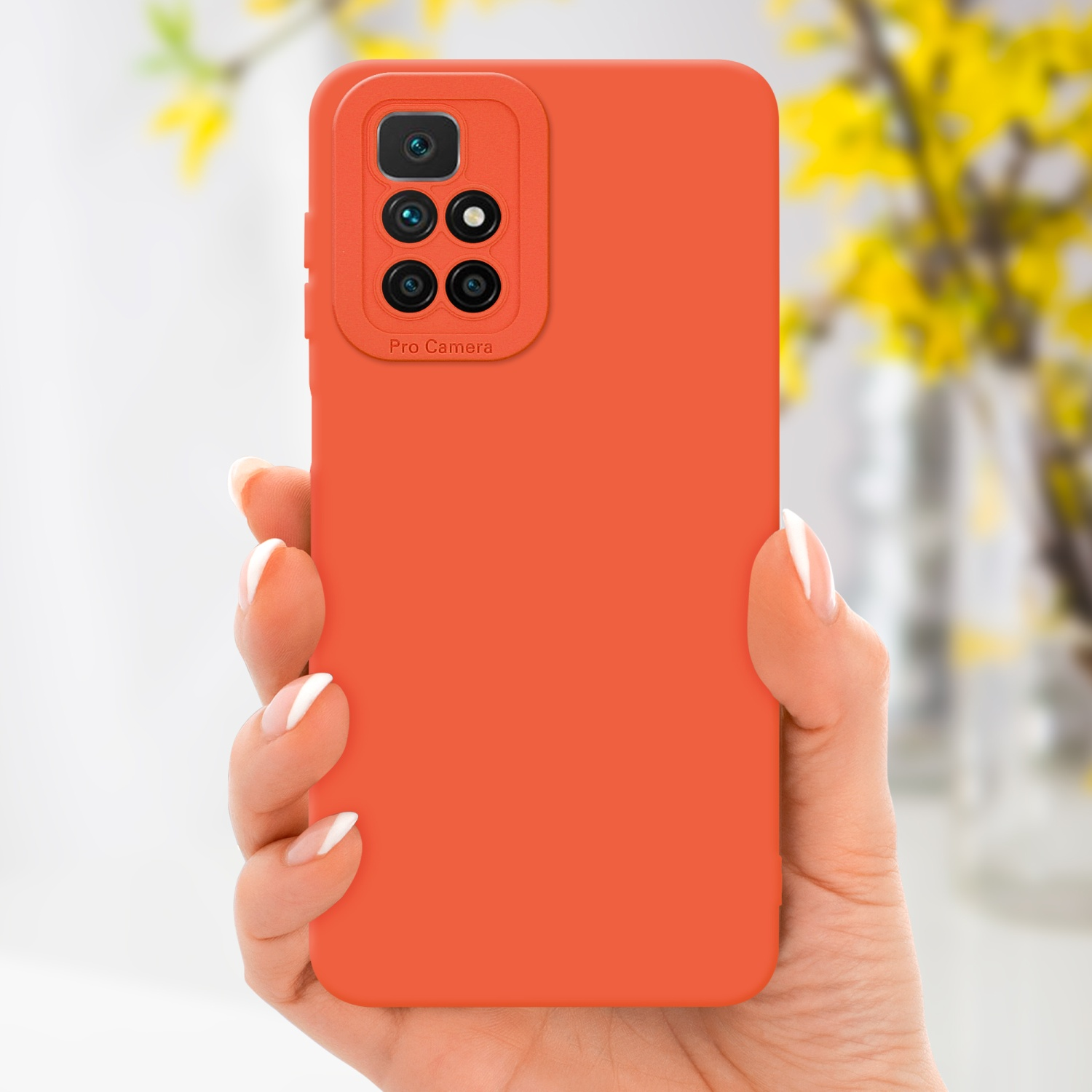 Main tenant une coque de téléphone orange avec une caméra pro, fleurs jaunes en arrière-plan.