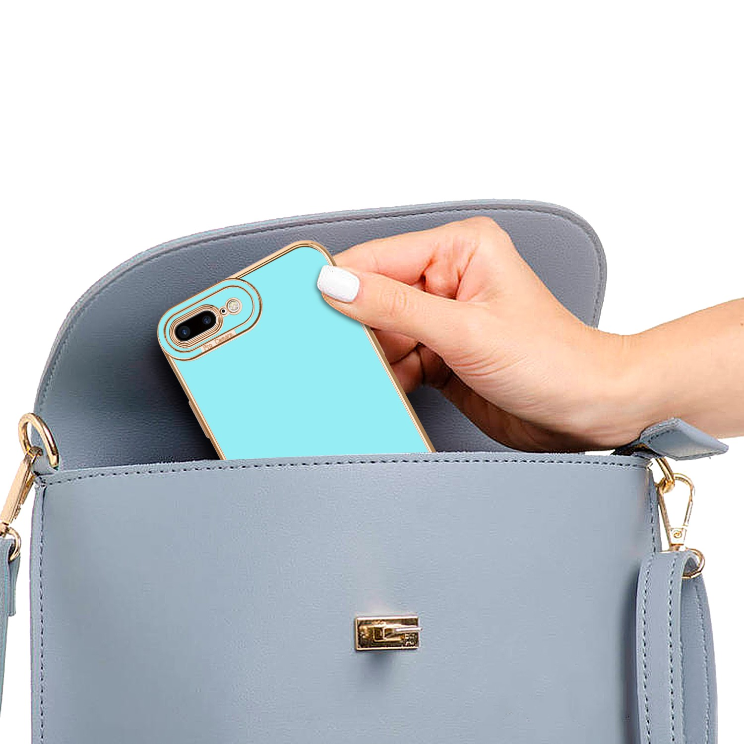 Hand hält ein hellblaues Telefon in einer blauen Handtasche. Das Telefon hat eine goldene Kante und Kameras.