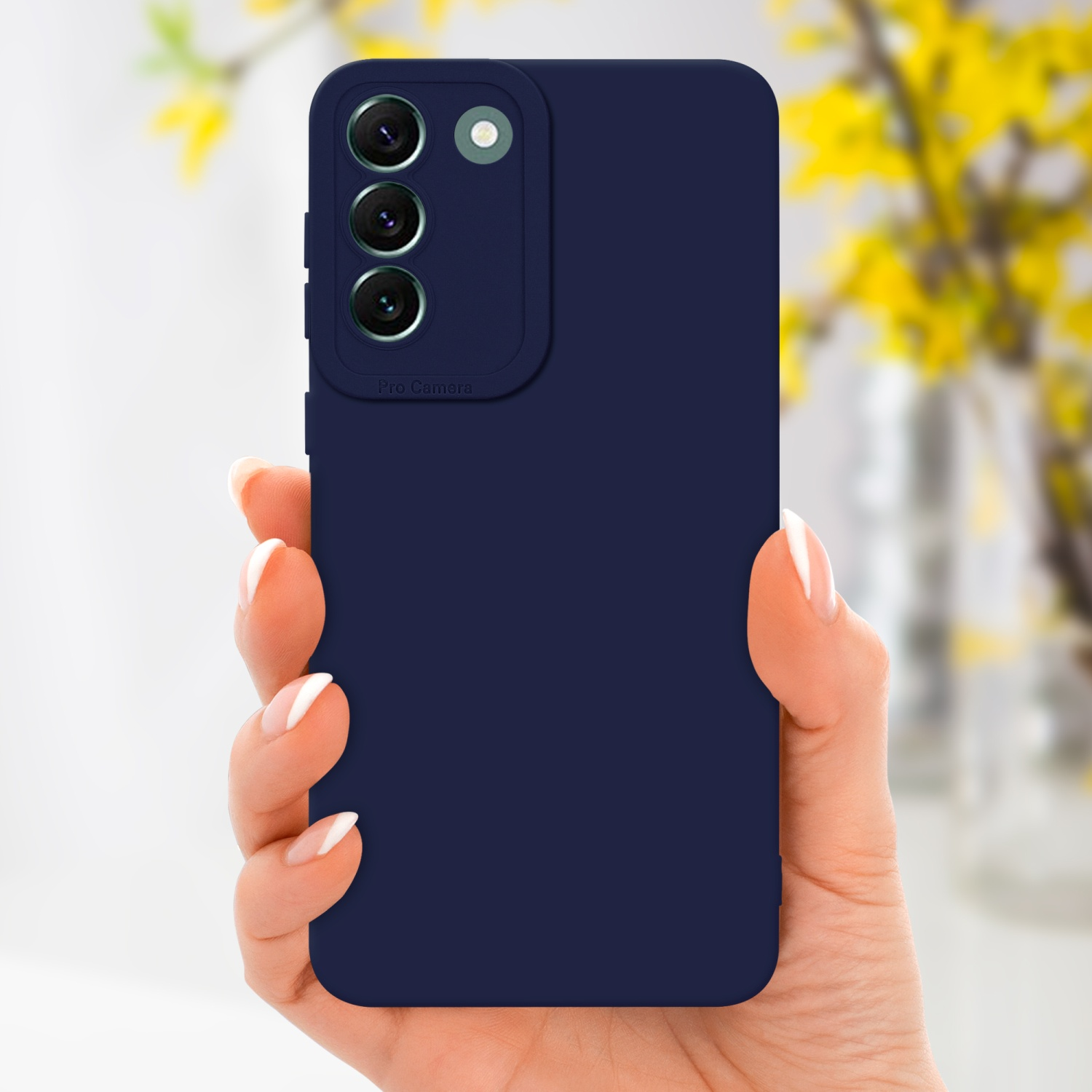 Mano che tiene un telefono blu navy con sporgenza della fotocamera. Fiori gialli sfocati sullo sfondo.