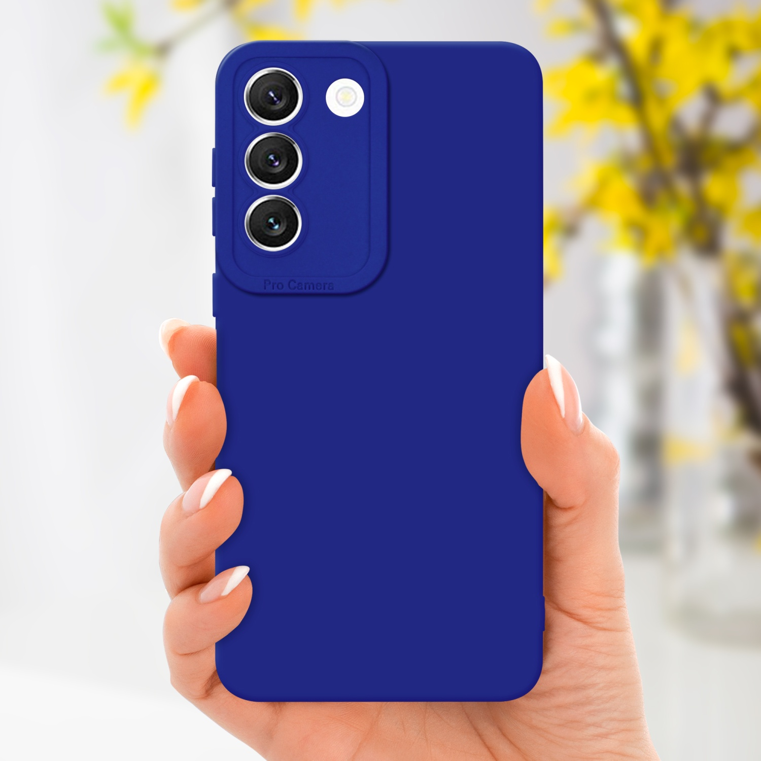 Main tenant un téléphone bleu avec triple caméra et coque bleue, fleurs jaunes floues.