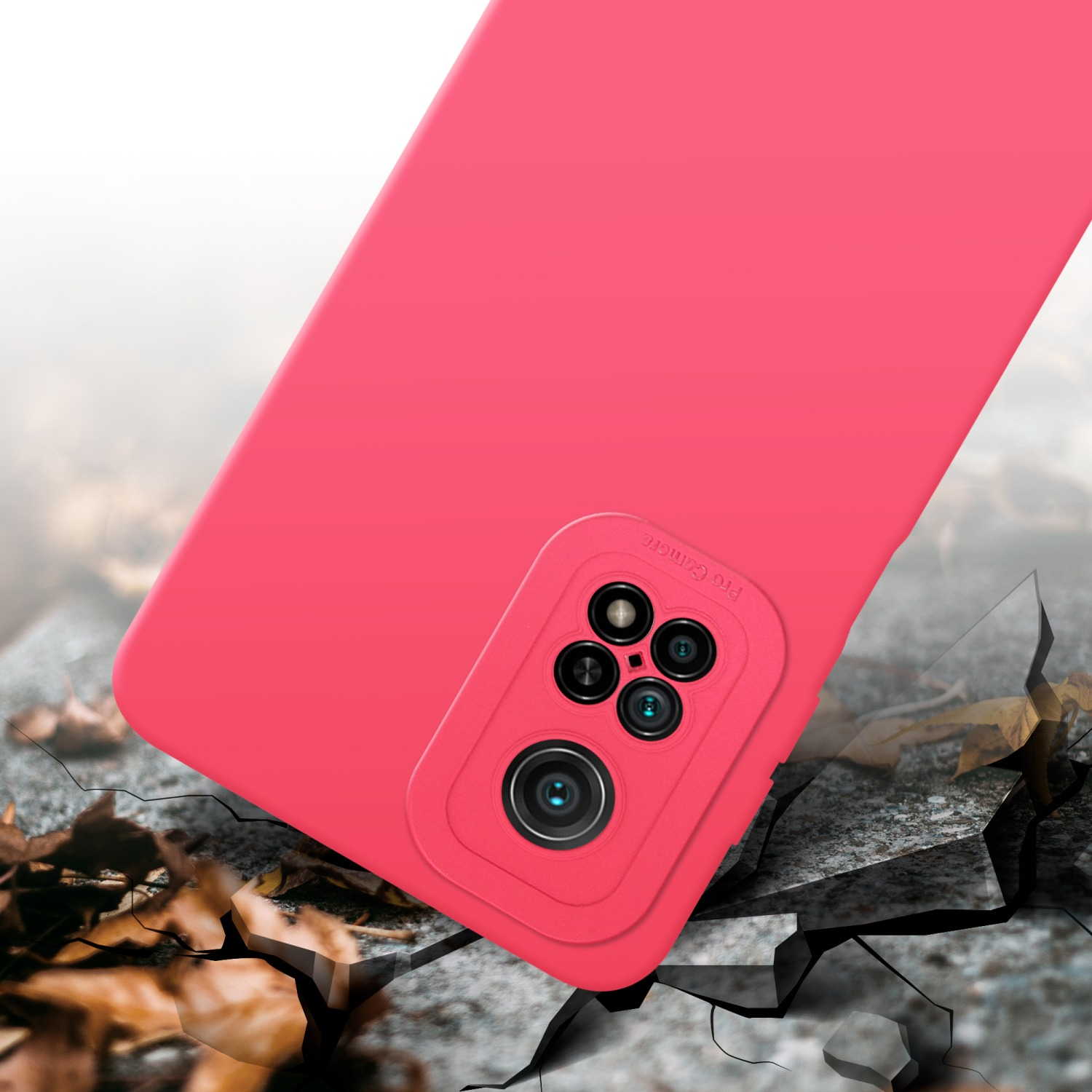 Custodia per telefono rosa con protuberanza della fotocamera, posizionata su terreno crepato con foglie sullo sfondo.