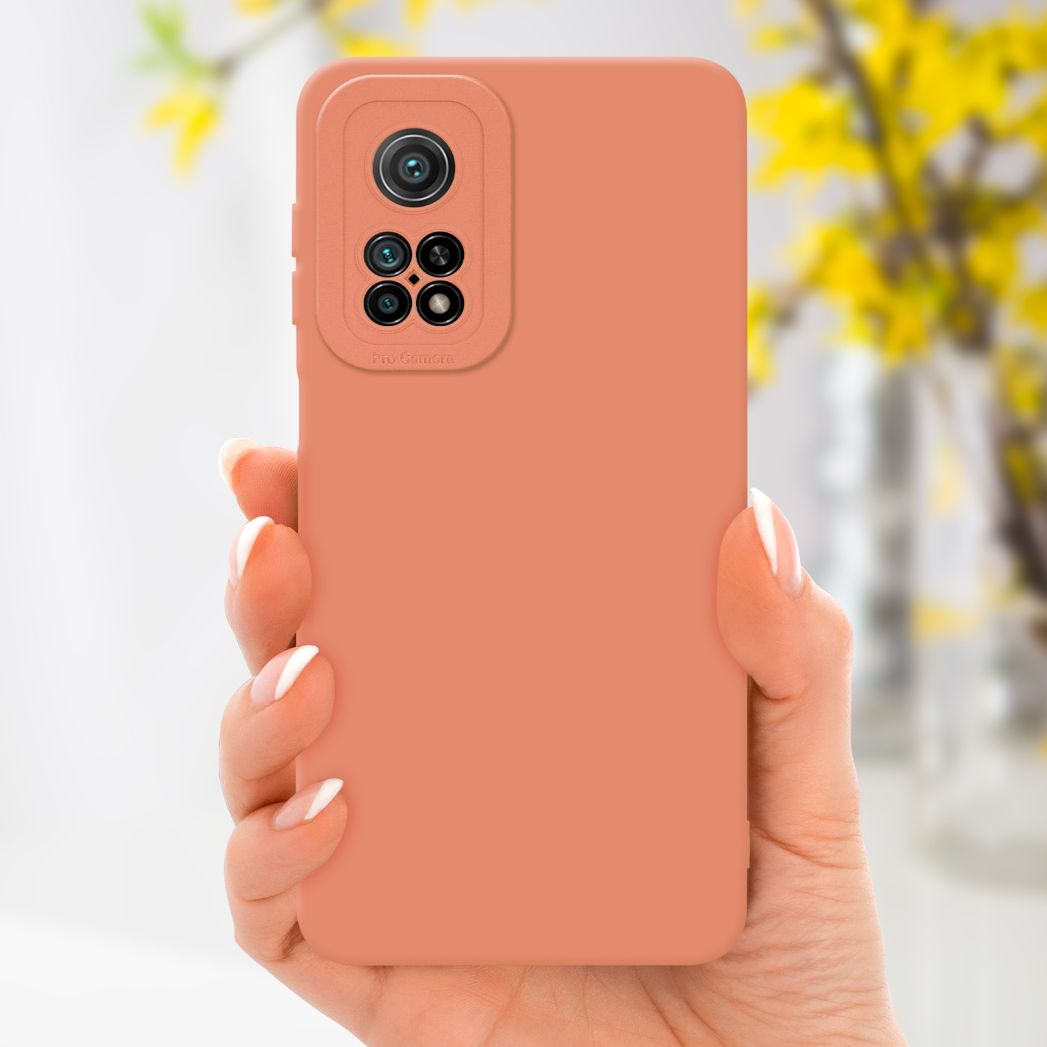 Una mano che tiene una custodia rosa per telefono con un telefono. La custodia è rosa. Fiori gialli sullo sfondo.