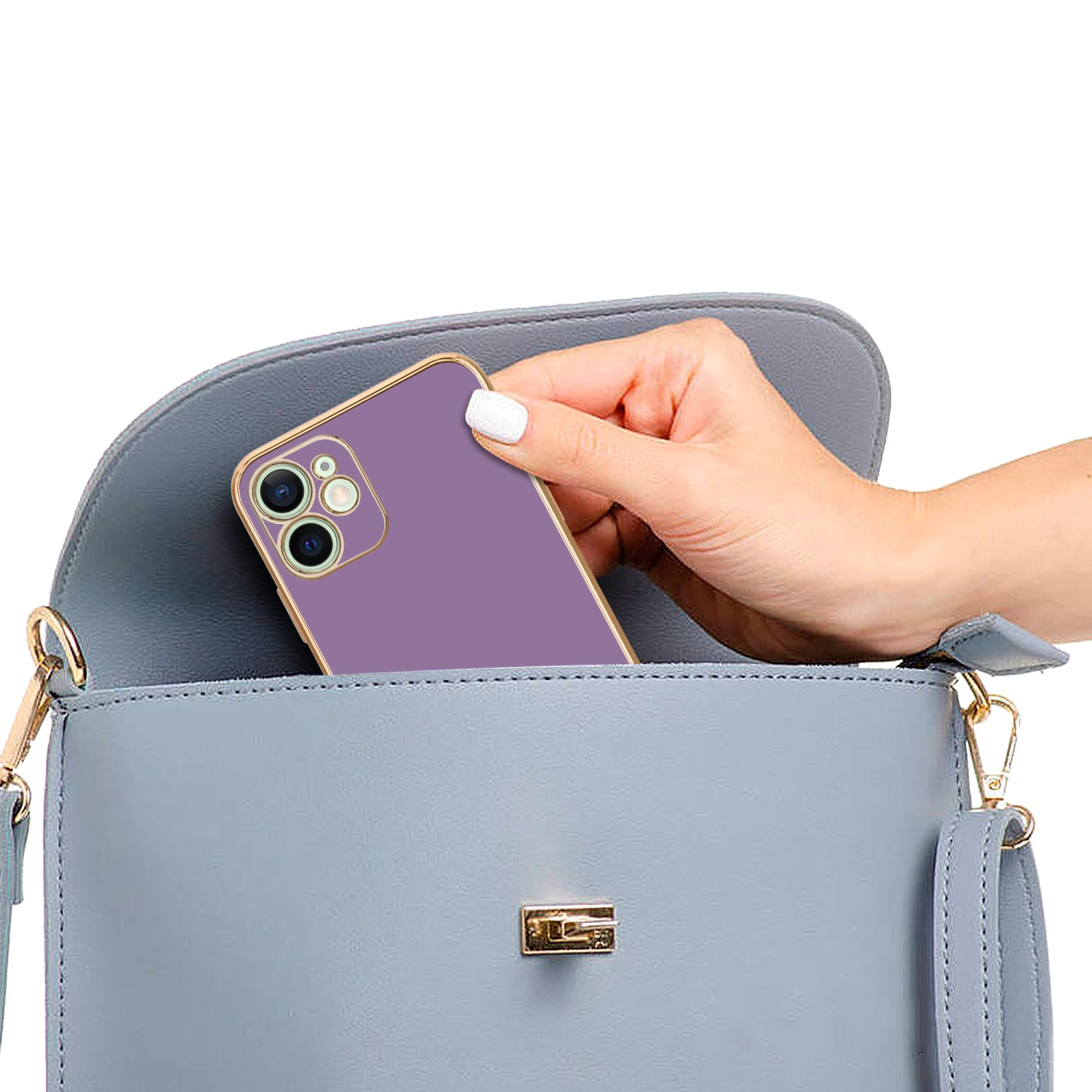 Eine Hand legt ein lila Telefon mit goldenem Rand in eine hellblaue Handtasche. Die Handtasche ist geöffnet.