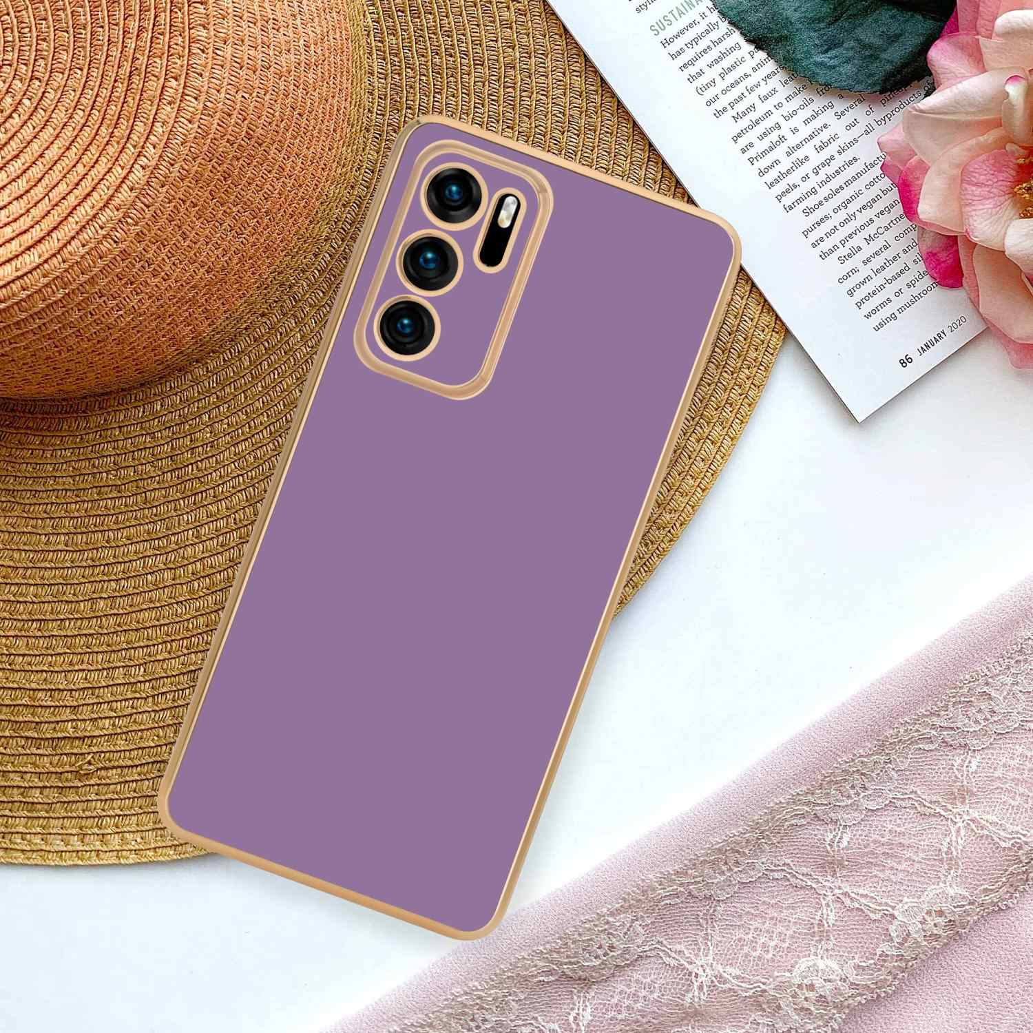 Ein Telefon in lila Hülle mit Strohhut, Zeitschrift und rosa Stoff.