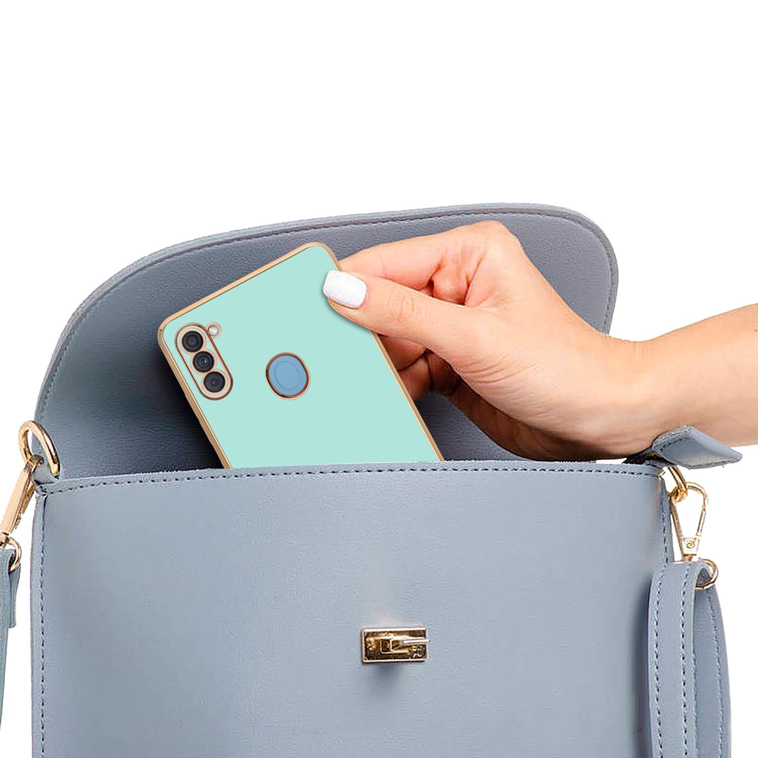 Eine Hand legt eine hellblaue Handyhülle in eine hellblaue Handtasche. Weißer Nagellack ist sichtbar.