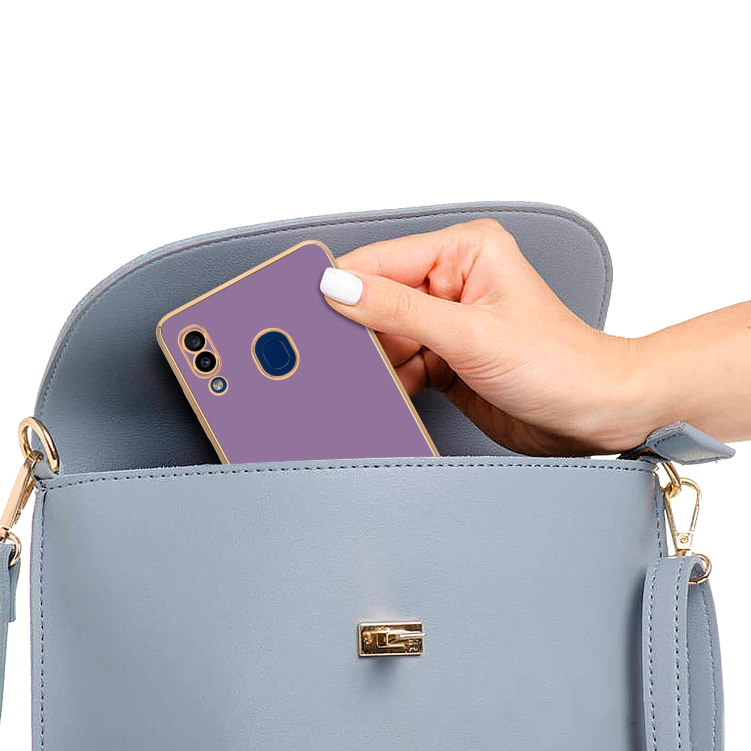 Hand legt eine lila Handyhülle in eine hellblaue Handtasche. Die Handtasche hat einen goldenen Verschluss.