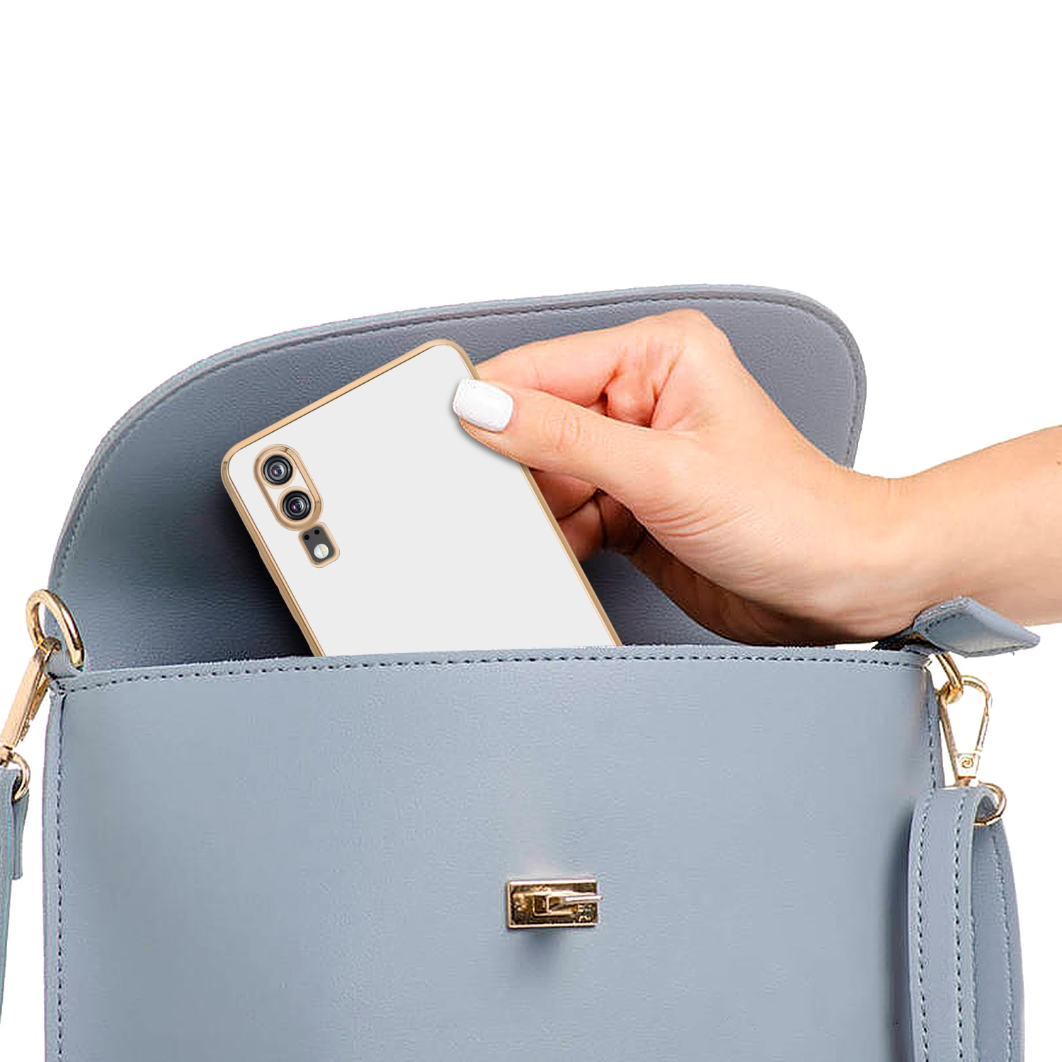 Hand, die ein weißes Telefon mit goldfarbenem Rand hält, das in eine blaue Handtasche gelegt wird.