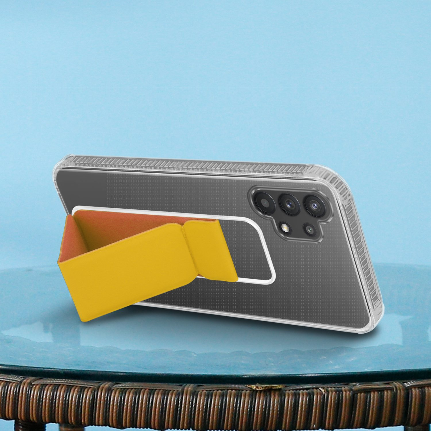 Ein Telefon mit gelbem und orangefarbenem Ständer liegt auf einem Tisch vor blauem Hintergrund.
