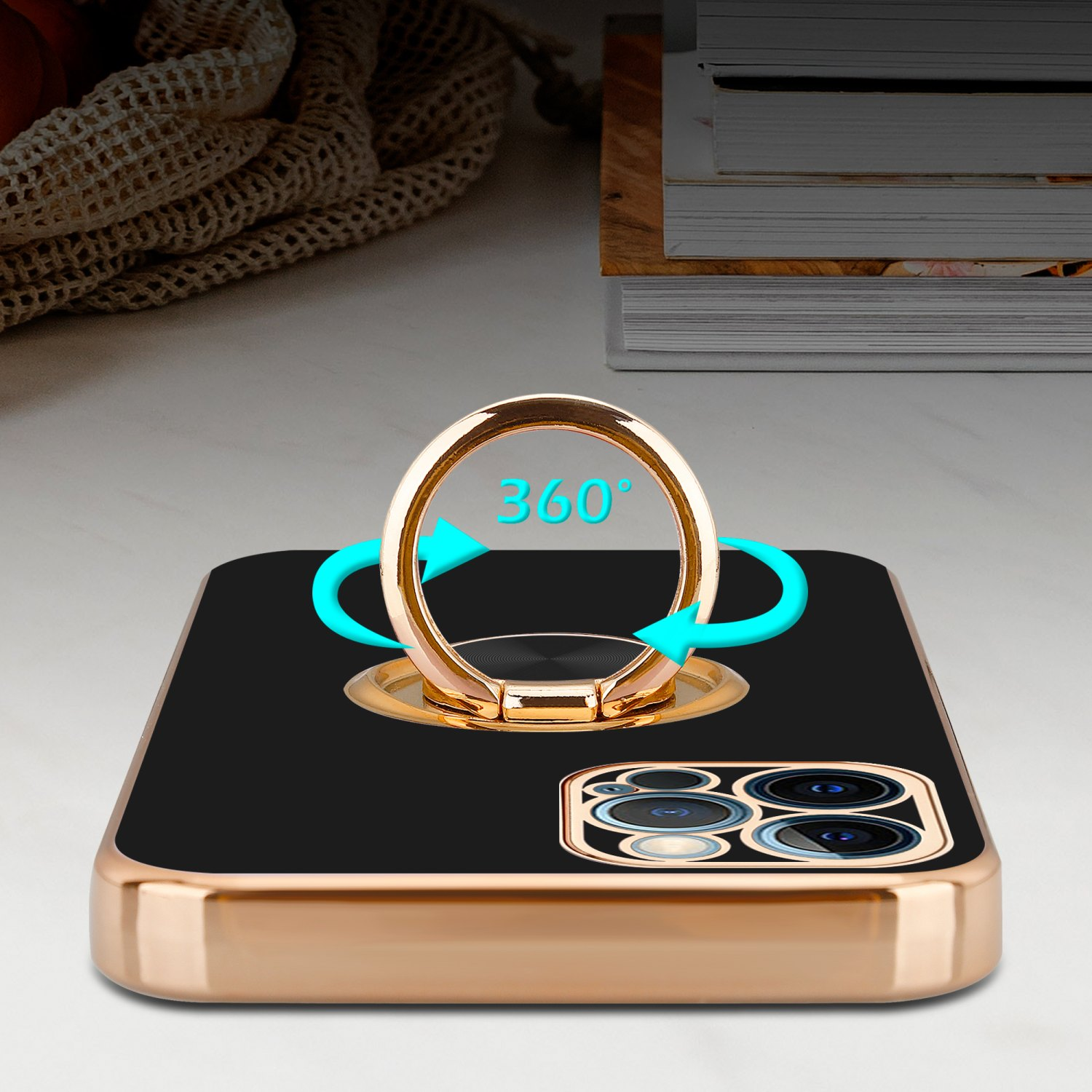 Schwarzes und goldenes Telefon mit drehbarem Ringhalter. 360° in blauen Pfeilen. Bücher auf weißer Oberfläche.
