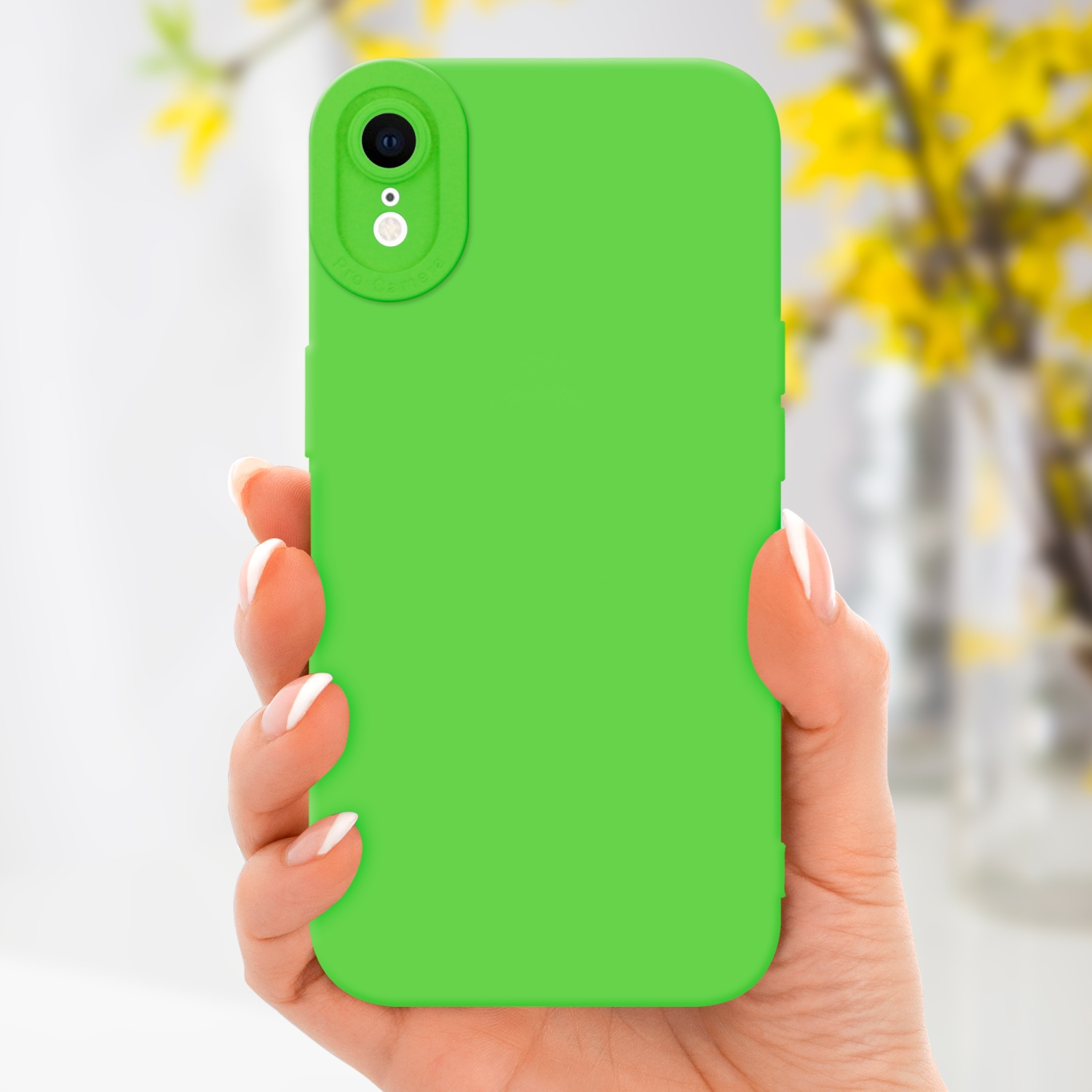 Custodia verde per telefono tenuta in mano. Fiori gialli sfocati sullo sfondo.