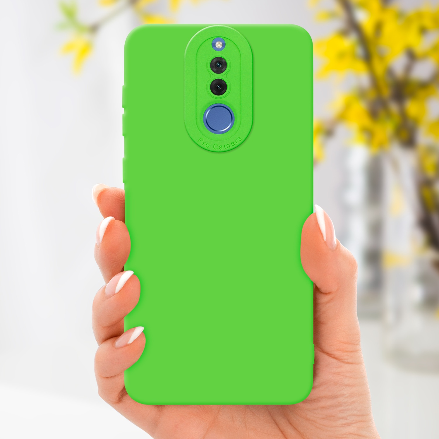 Una mano che tiene una custodia verde per telefono con una sezione fotocamera professionale. Fiori gialli sullo sfondo.