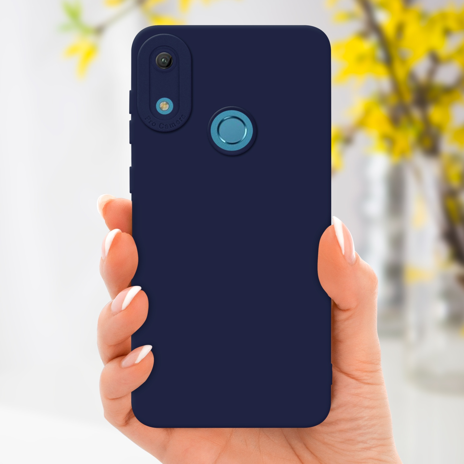 Main tenant un étui de téléphone bleu marine. Fleurs jaunes floues en arrière-plan.