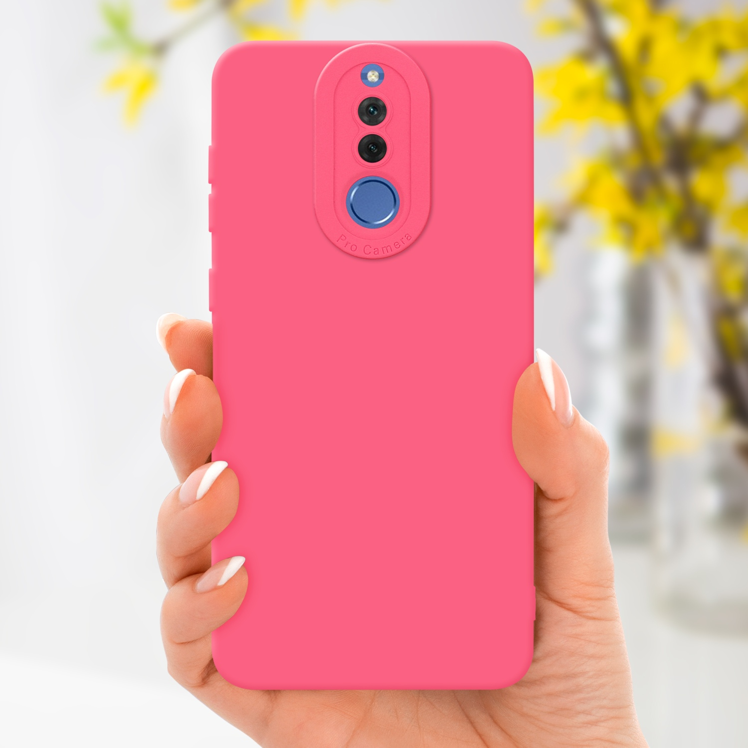 Una mano che tiene una custodia rosa per telefono con una sezione fotocamera professionale. Fiori gialli sullo sfondo.