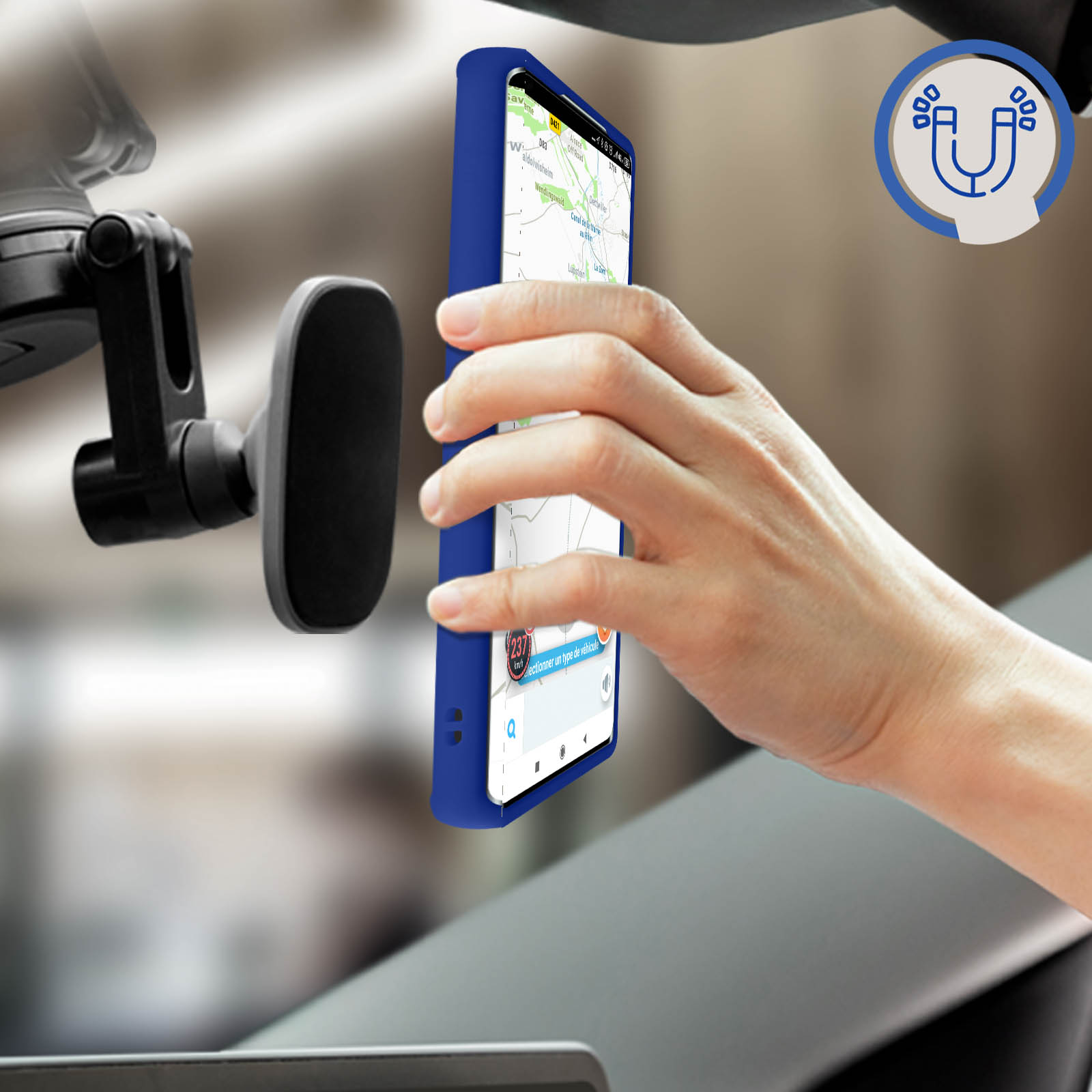 Mano che tiene un telefono con una mappa sullo schermo vicino a un supporto per auto. Il telefono ha una custodia blu.
