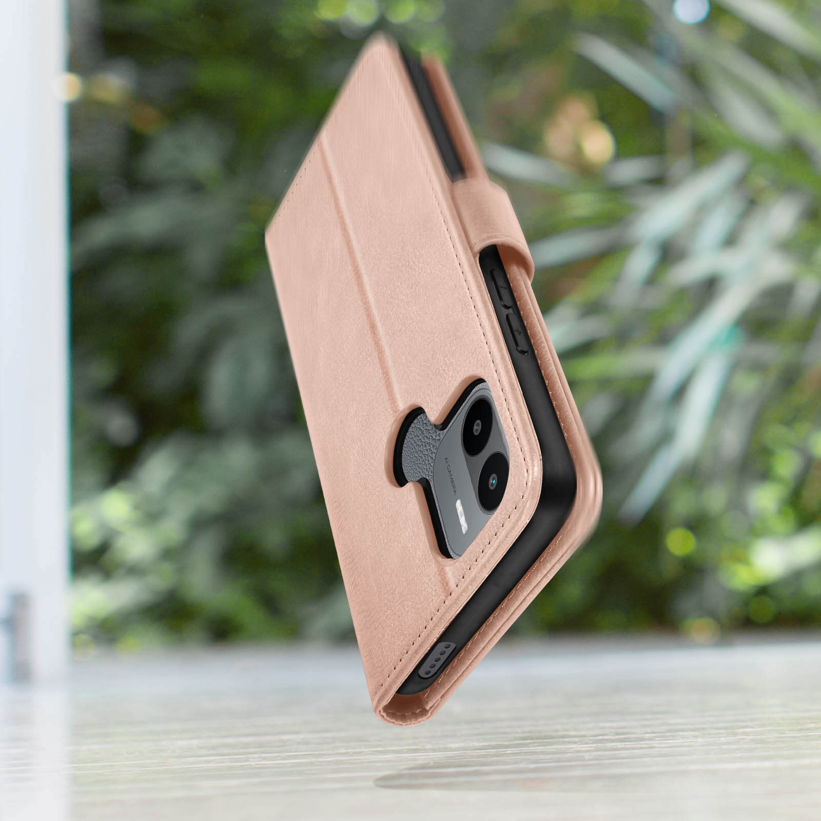 Una custodia per telefono rosa con chiusura magnetica, un telefono all'interno e uno sfondo verde sfocato.