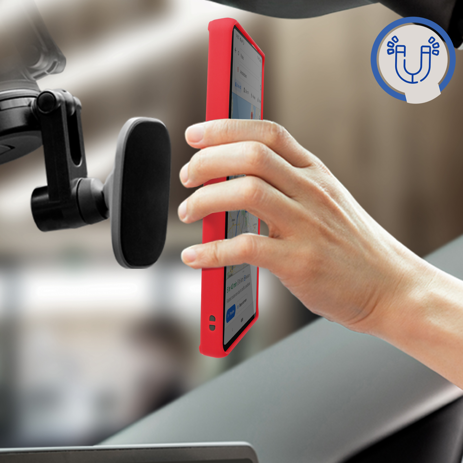 Een hand die een rode telefoon in een auto vasthoudt. Een magnetische telefoonhouder is zichtbaar.