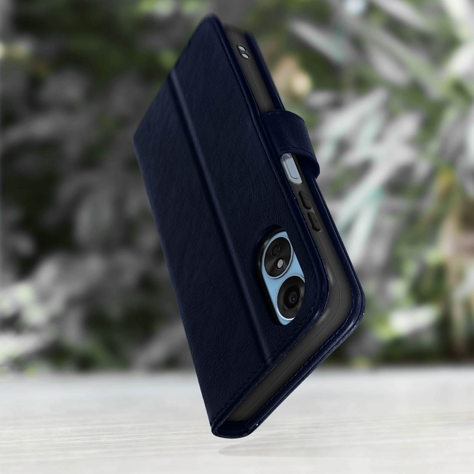 Telefono blu navy in una custodia a portafoglio. Sfondo verde sfocato. Superficie in legno.