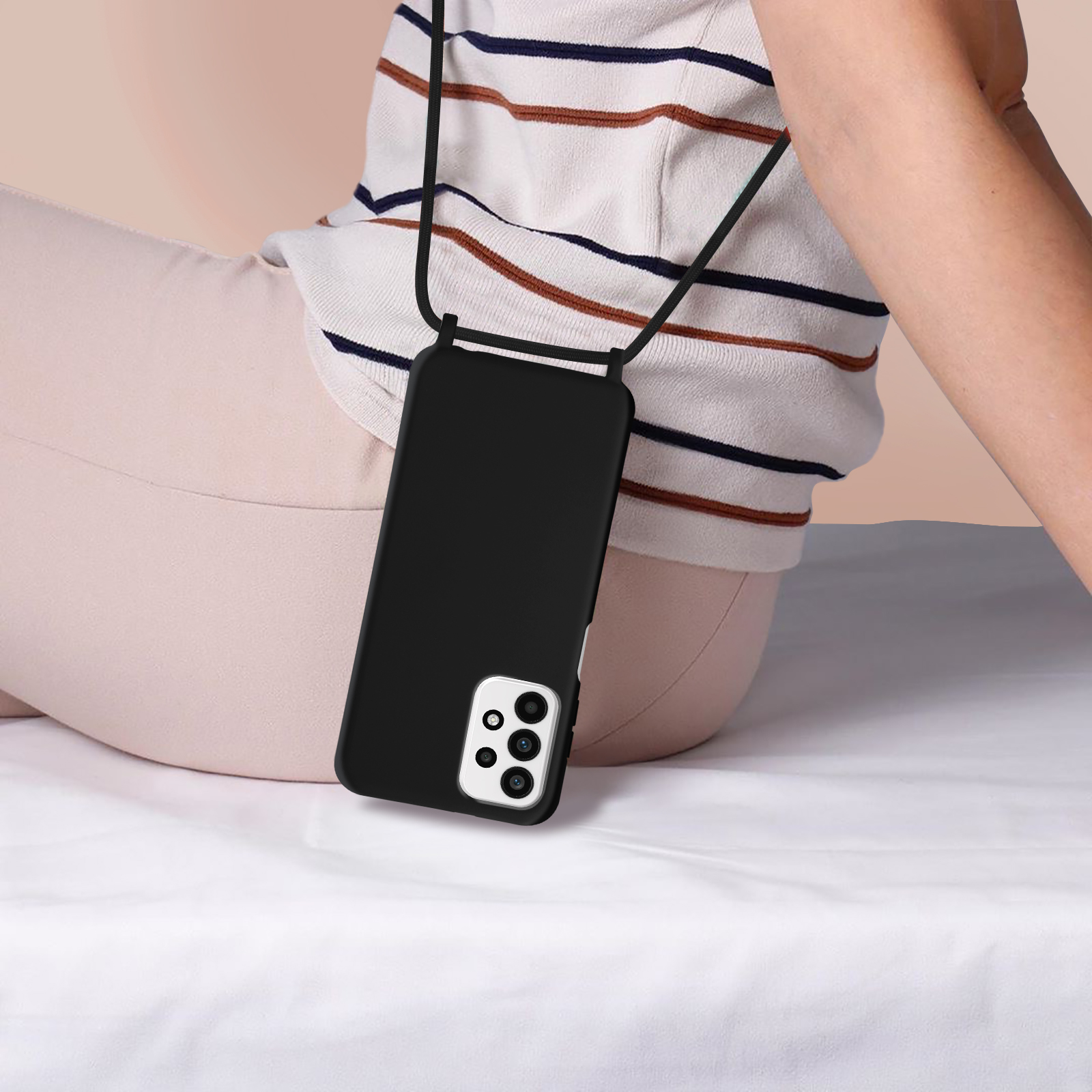 Personne avec étui de téléphone noir et lanière, assise sur un drap blanc. Chemise rayée beige et blanche.
