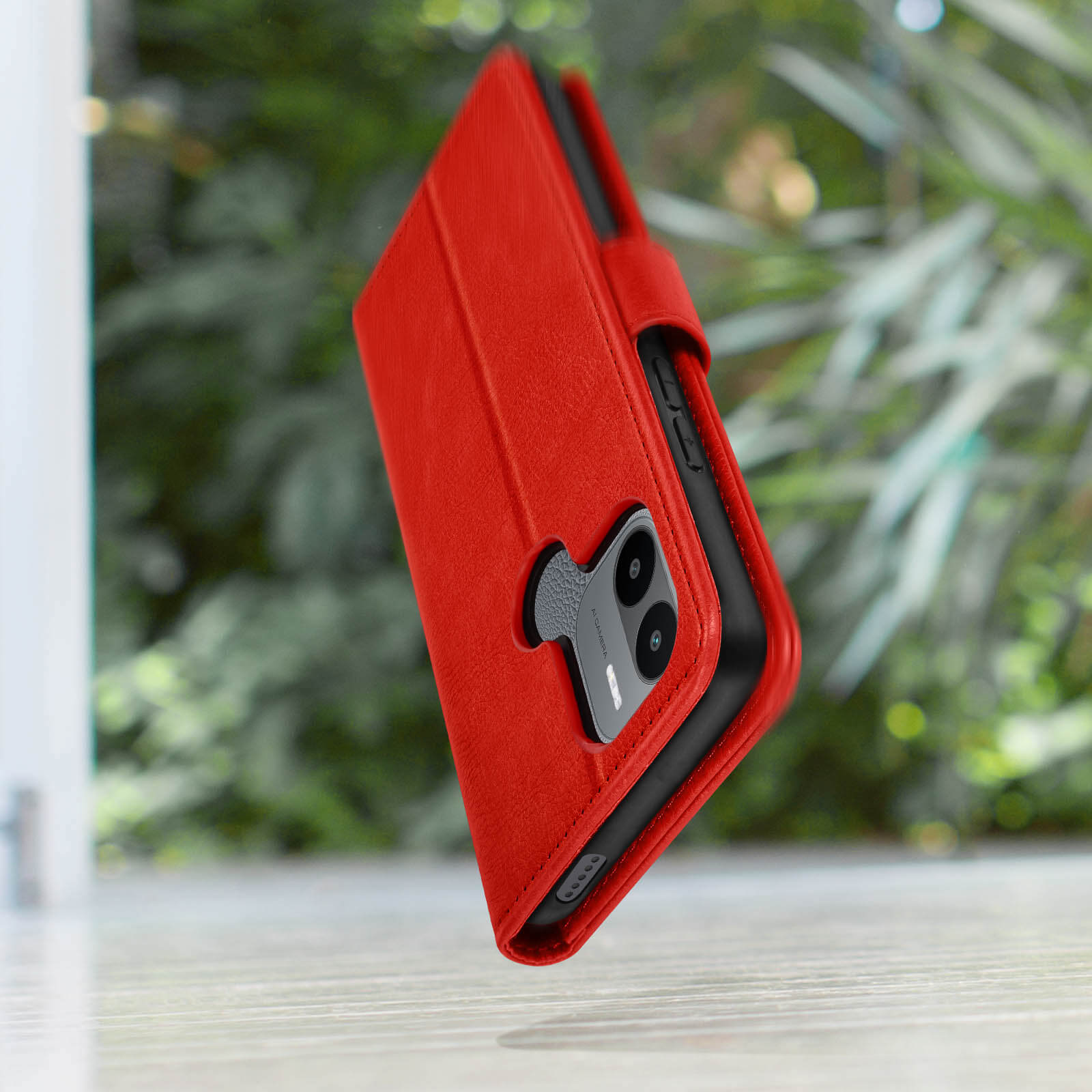 Una custodia rossa per telefono con design a portafoglio, su uno sfondo verde sfocato.