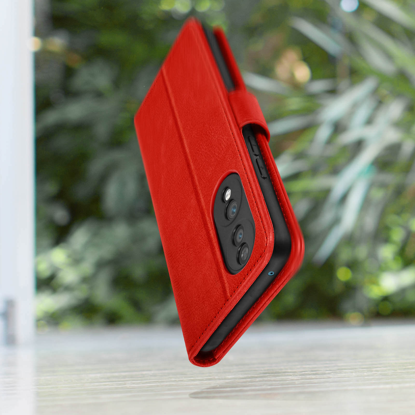 Custodia rossa, aperta per rivelare il telefono, con sfondo sfocato.