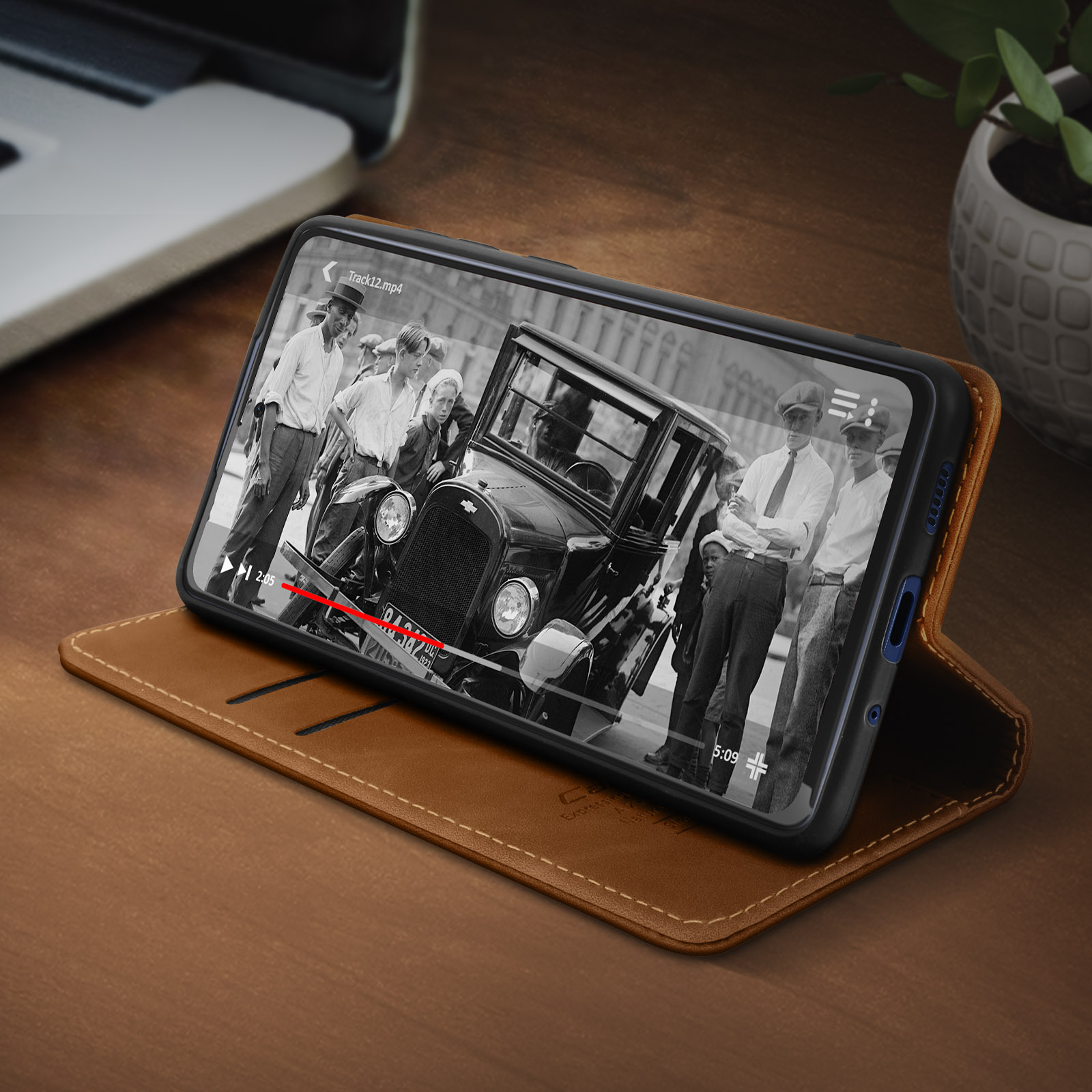 Smartphone in einer braunen Lederhülle, das eine Oldtimer-Szene aus einem Film zeigt.