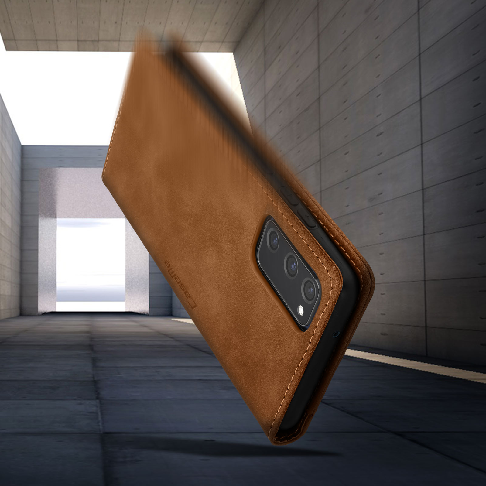 Telefon in brauner Lederhülle, stürzt. Der Hintergrund ist eine Betonmauer.