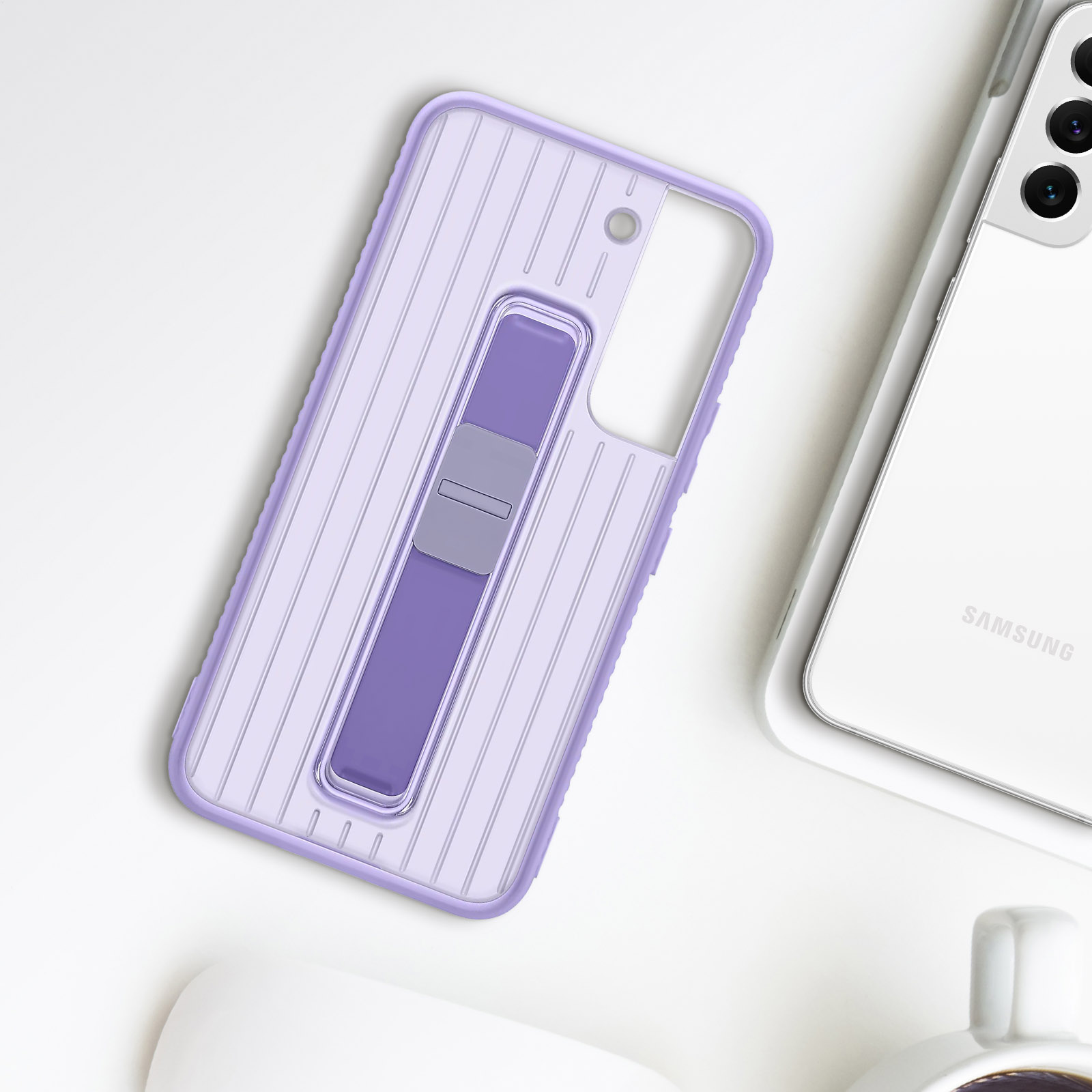 Helllila Handyhülle mit Ständer, auf weißer Oberfläche neben weißem Handy.
