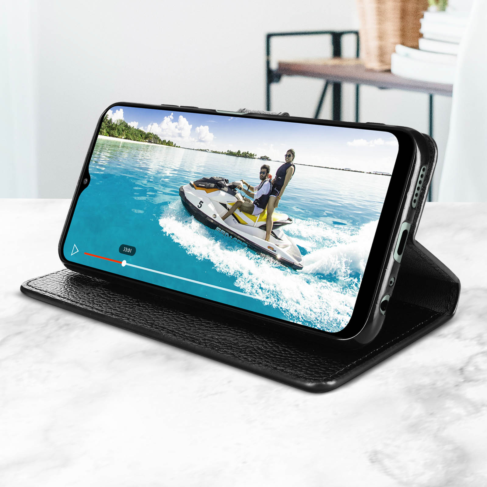 Ein Telefon zeigt ein Video eines Jetskis auf dem Wasser. Es steht auf einer schwarzen Hülle, nach oben abgewinkelt.