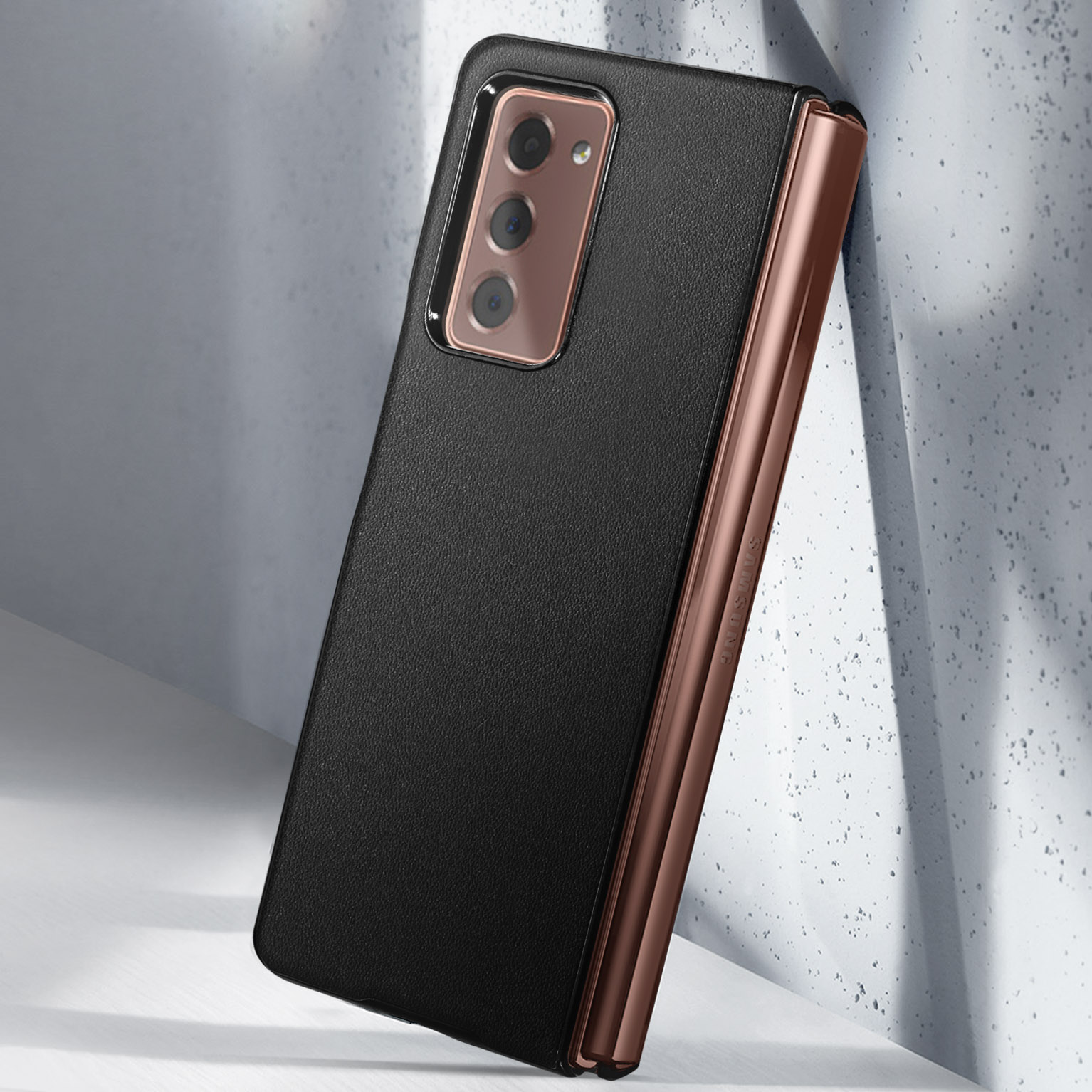 Custodia nera con cornice bronzo appoggiata a muro in cemento.