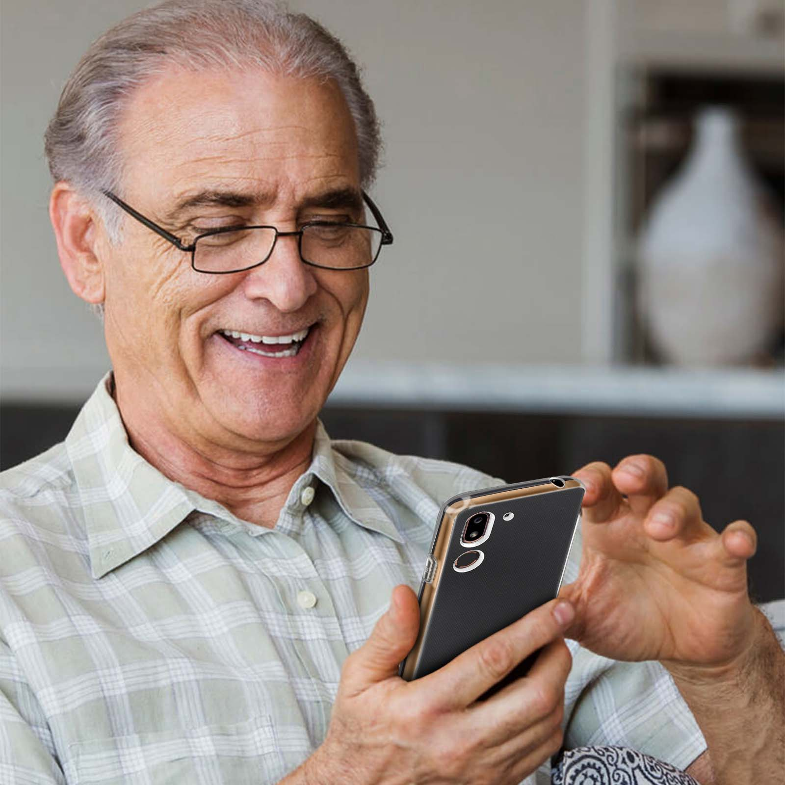 Lächelnder älterer Mann mit Brille, der auf ein Telefon blickt. Er hält das Telefon in seinen Händen.