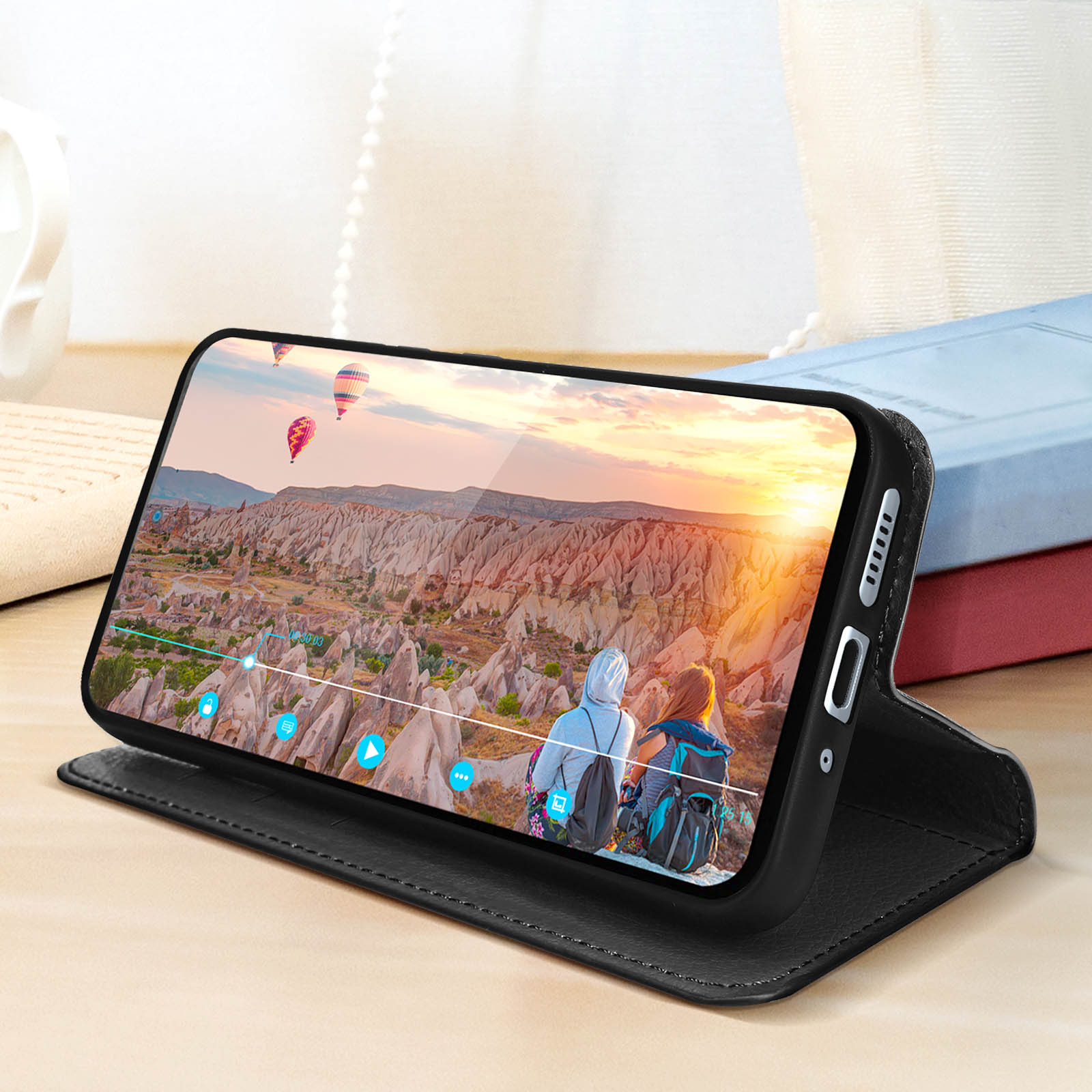 Zwarte telefoonhoes met een telefoon die een video laat zien van een landschap met mensen.