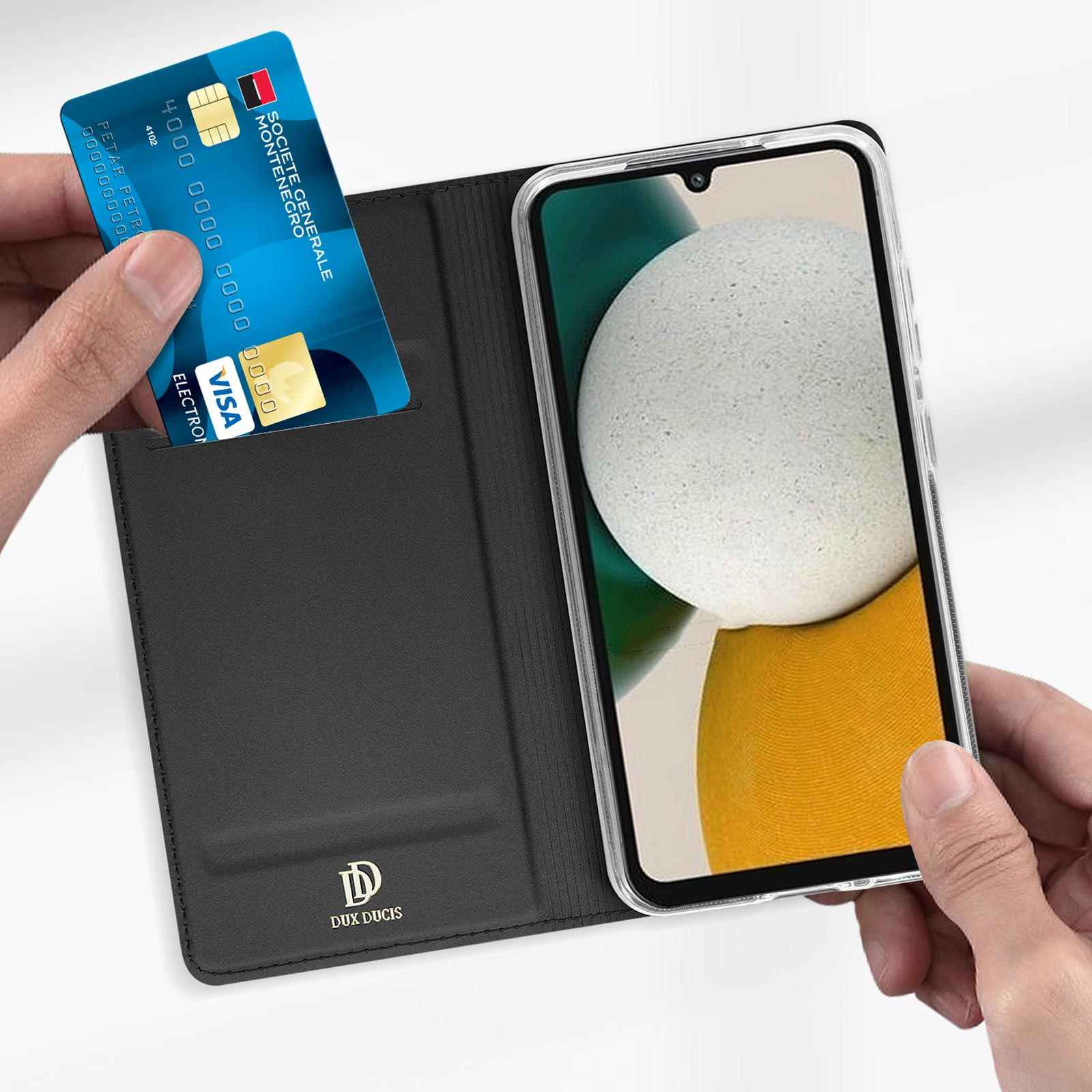 Eine Hand hält eine blaue Kreditkarte und eine Handyhülle mit Telefon.