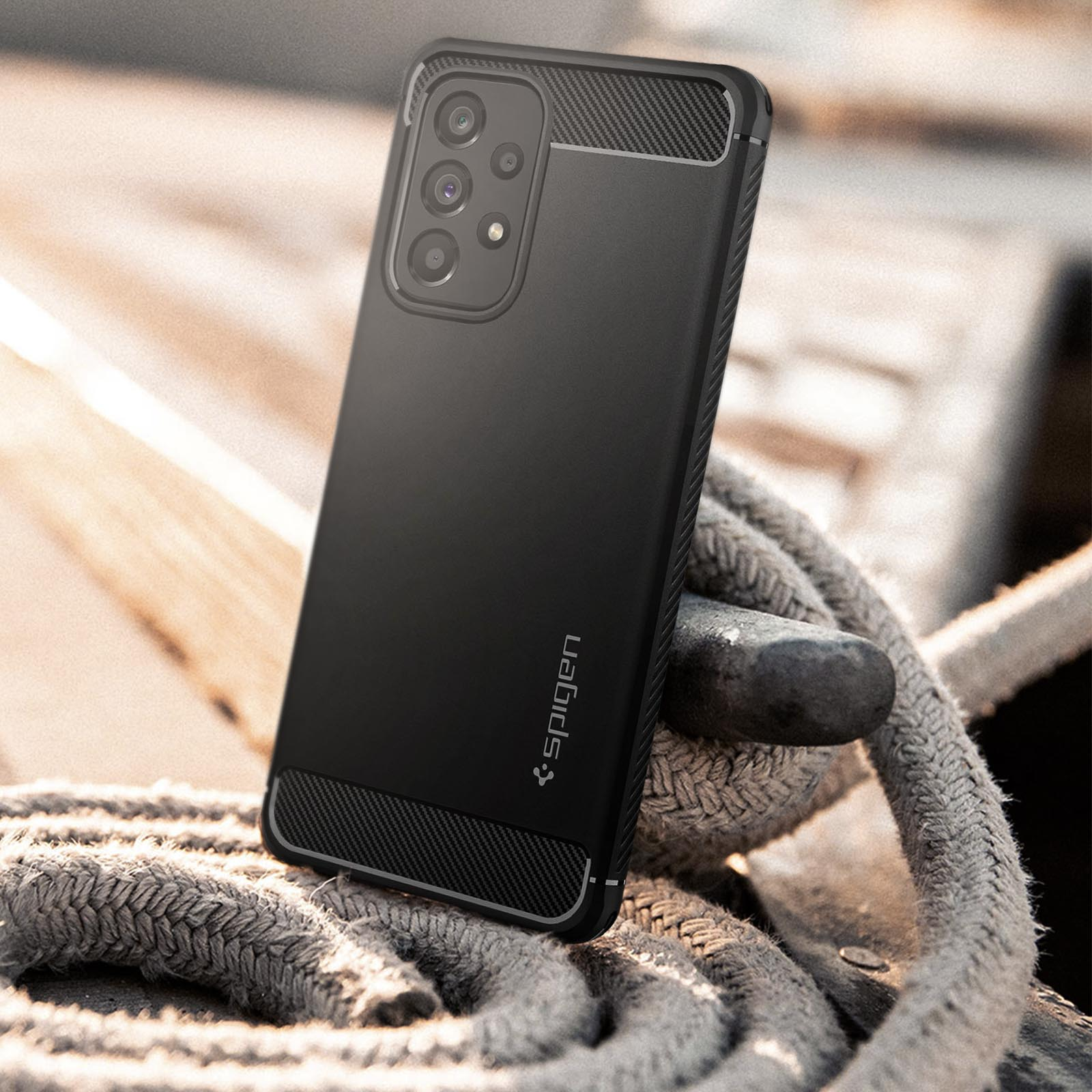Una custodia nera Spigen su un telefono, su una superficie in legno con corda.
