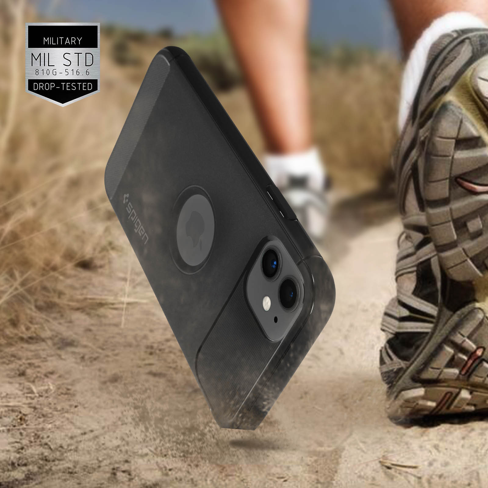 Custodia nera per telefono su uno sterrato. Etichetta di test di caduta di grado militare visibile. Scarpa sullo sfondo.