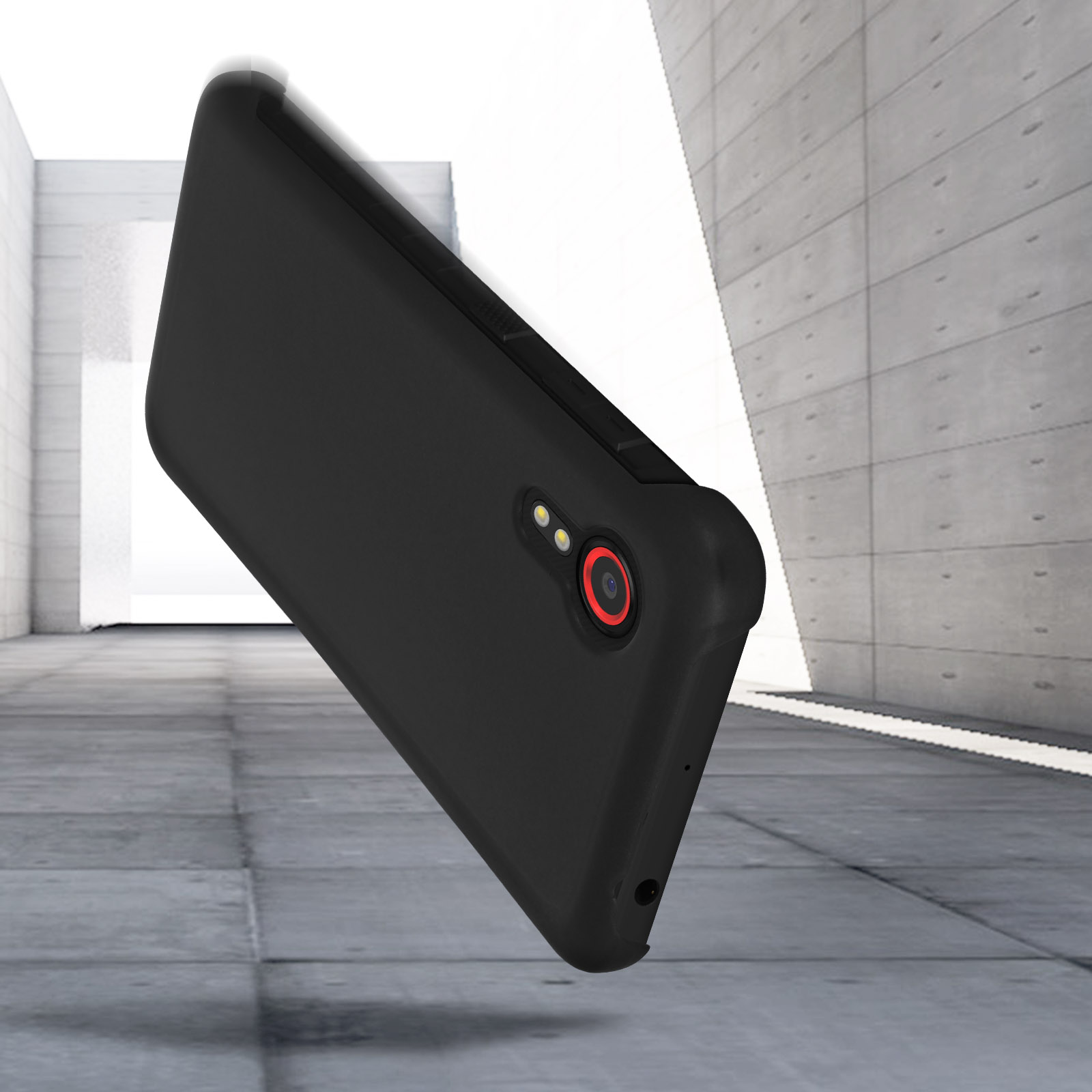Custodia nera per telefono su cemento grigio. La custodia ha un anello rosso per la fotocamera.